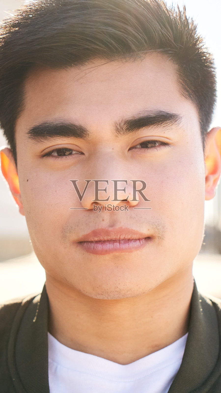 一名亚洲男子的户外肖像，一脸严肃，神情紧张地看着镜头。一个宁静的人脸特写-真实的人和情感的概念。照片摄影图片