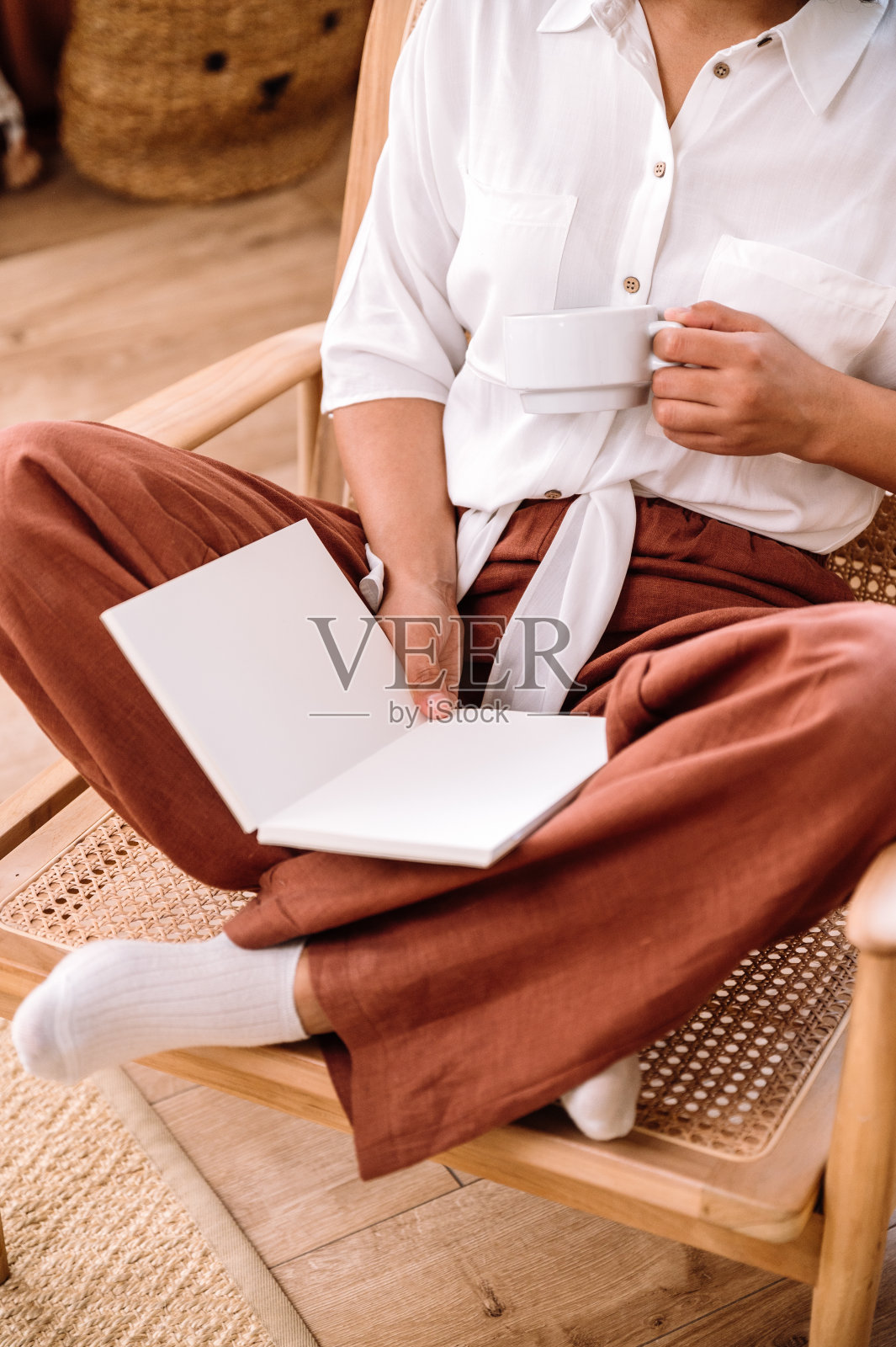 女人端着一杯咖啡坐在那里，手里拿着打开的笔记本照片摄影图片