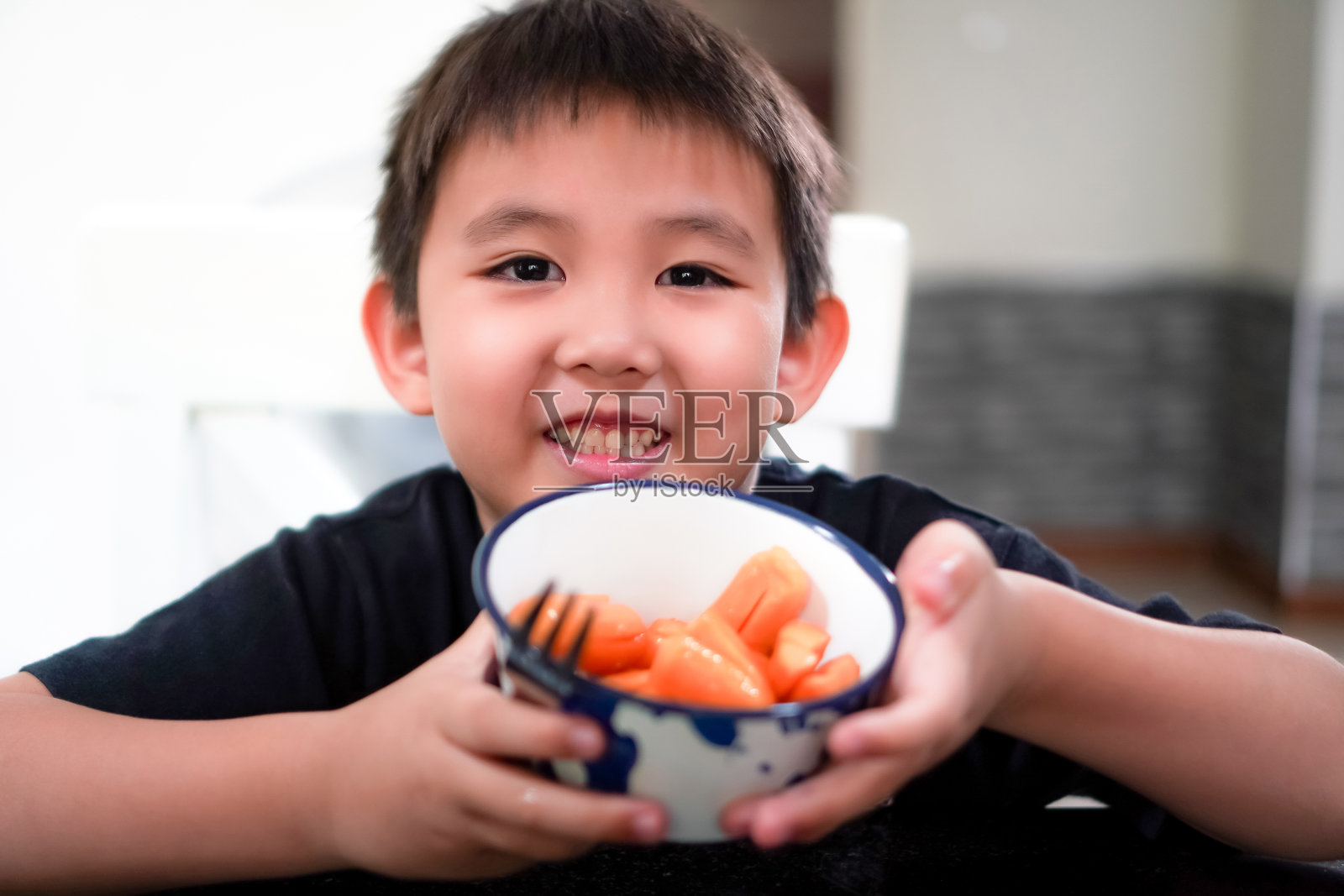 图为一个小男孩在妈妈做了油炸香肠当午餐后开心地笑着。照片摄影图片