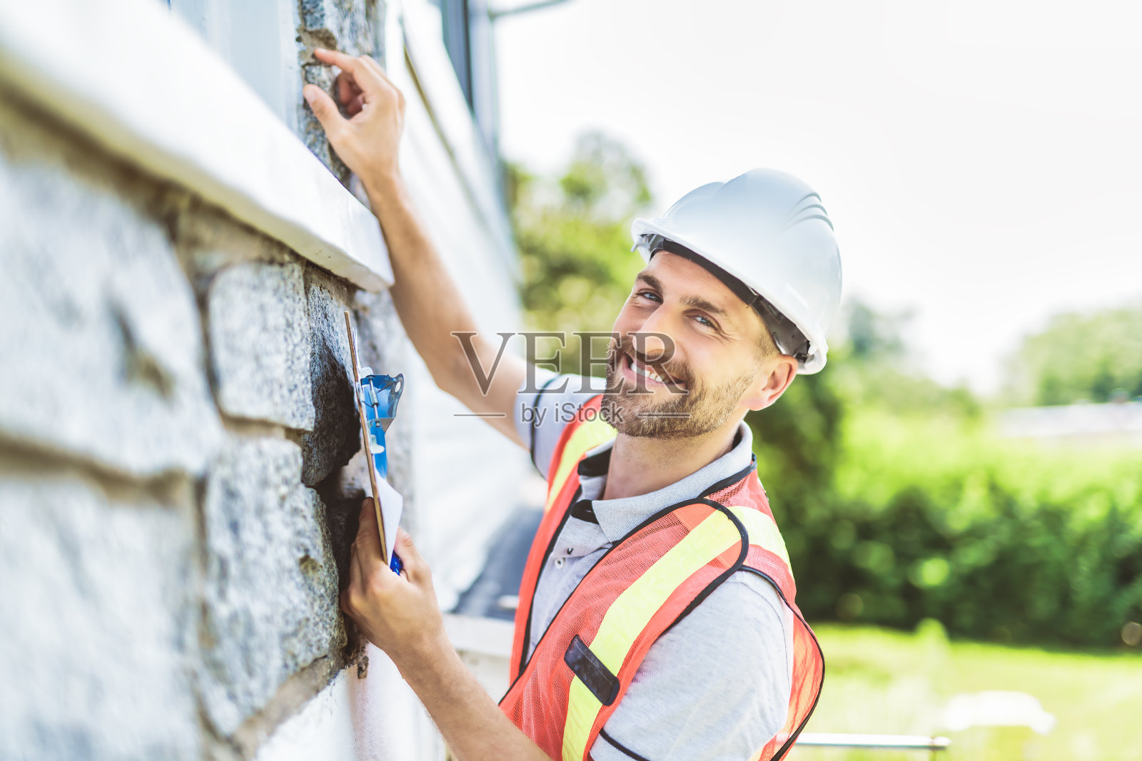 戴白色安全帽的人拿着写字板，检查房子照片摄影图片