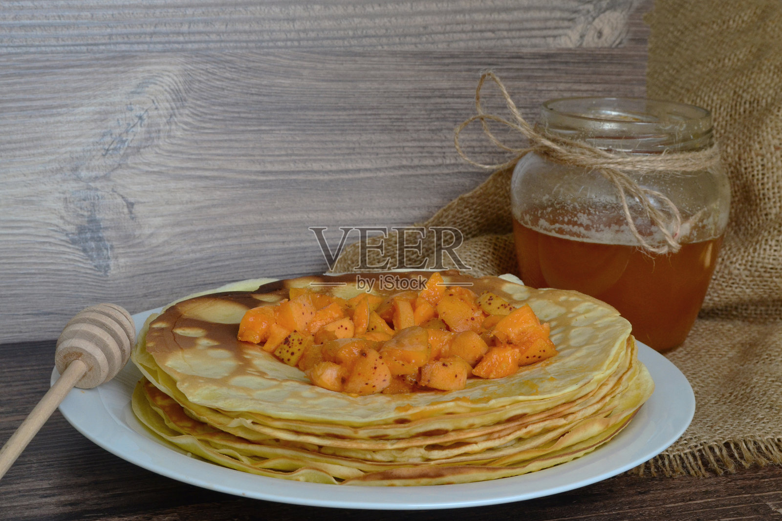 一盘薄煎饼，麻袋上放着杏子和蜂蜜照片摄影图片