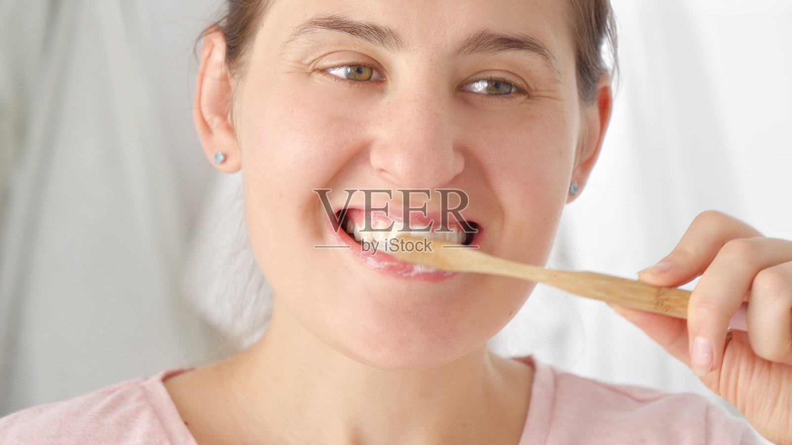 一个年轻的黑发女人正在用木制牙刷刷牙。牙齿健康观念，自我检查口腔及口腔卫生。照片摄影图片