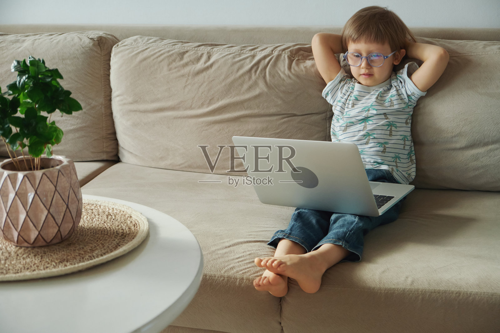 家庭教育，远程教育，孩子坐在沙发上使用笔记本电脑照片摄影图片