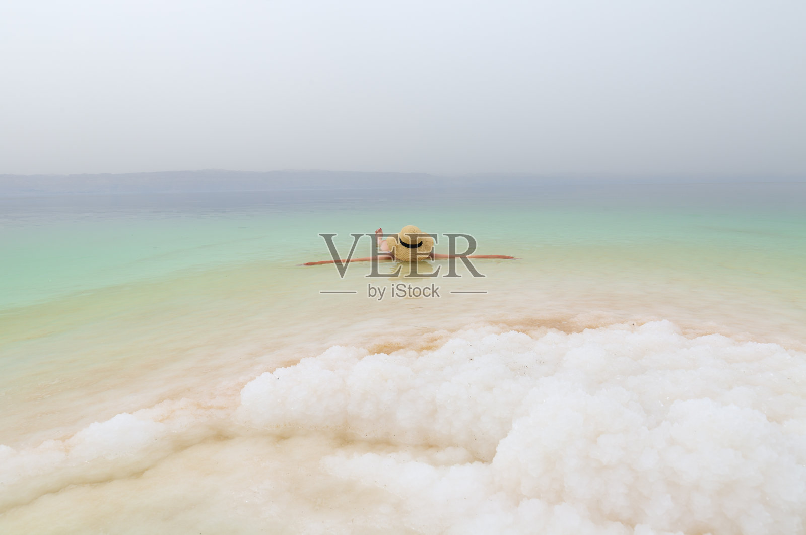 戴帽在死海放松游泳的女孩照片摄影图片