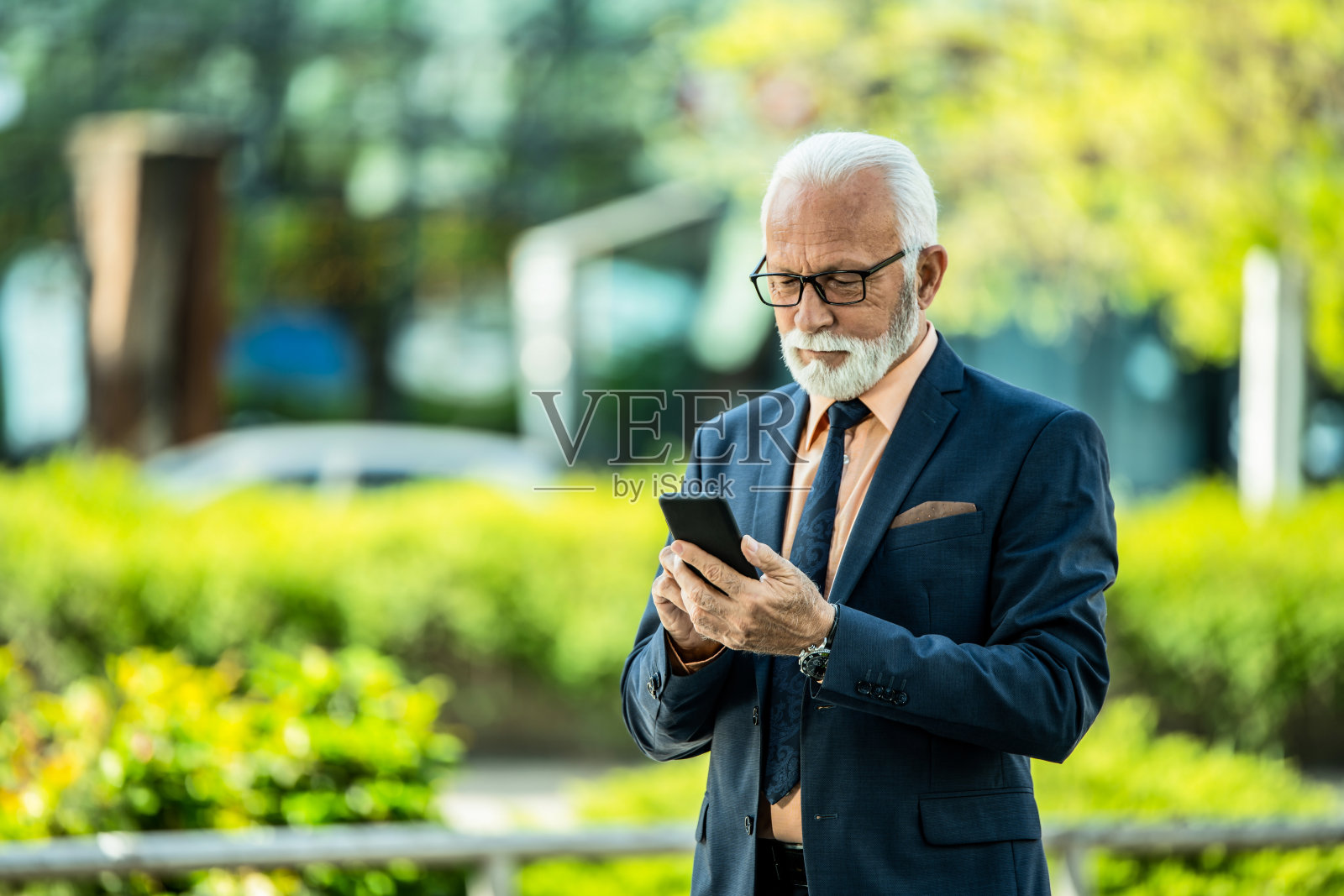 快乐的年长商人在城市街道上使用手机。照片摄影图片