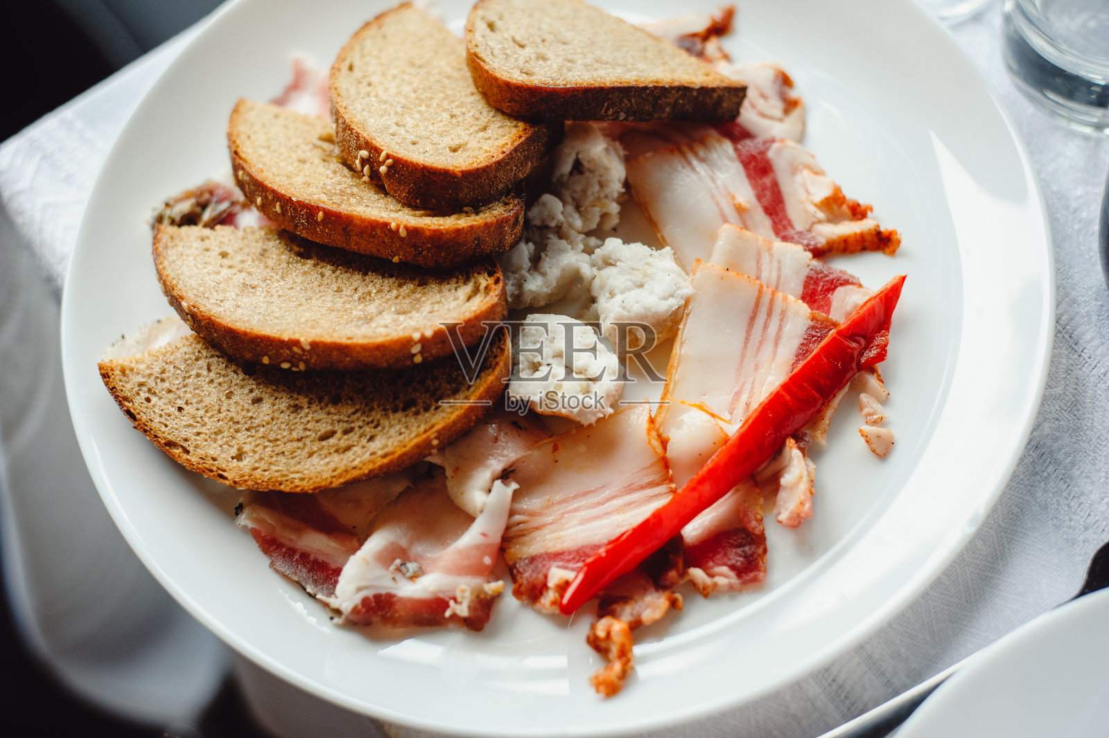 用草药干脂肪。猪油猪腹腔的脂肪，用于烹调或吃点心时使用并点燃猪油片和面包放在白色的盘子里。美味的小吃照片摄影图片
