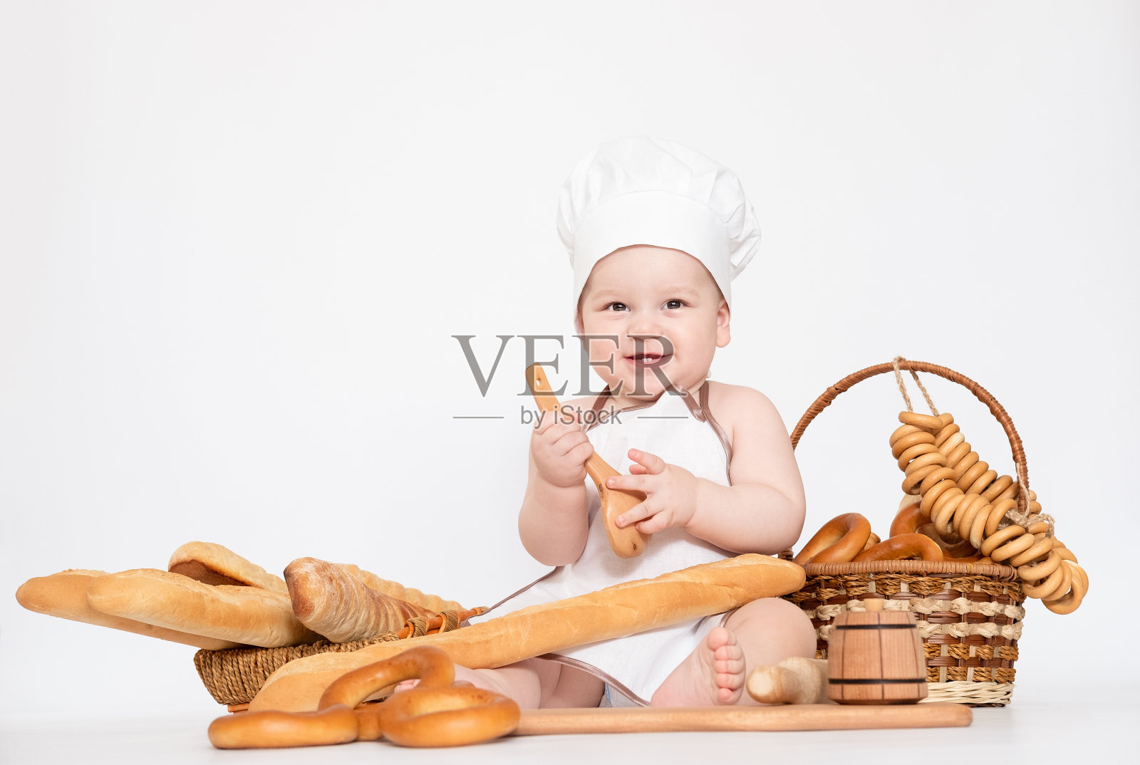 小男孩戴着厨师帽，拿着面包，是个有趣的小厨师照片摄影图片