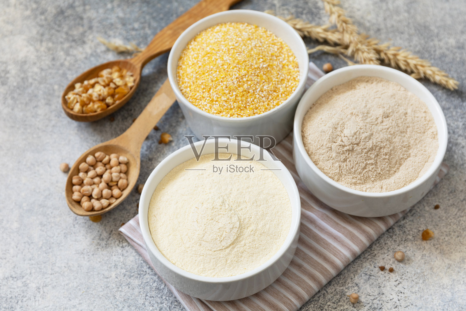 食品和烘焙无麸质成分。谷物和粗面粉，玉米粉，荞麦粉，鹰嘴豆粉在灰色的石头背景。照片摄影图片