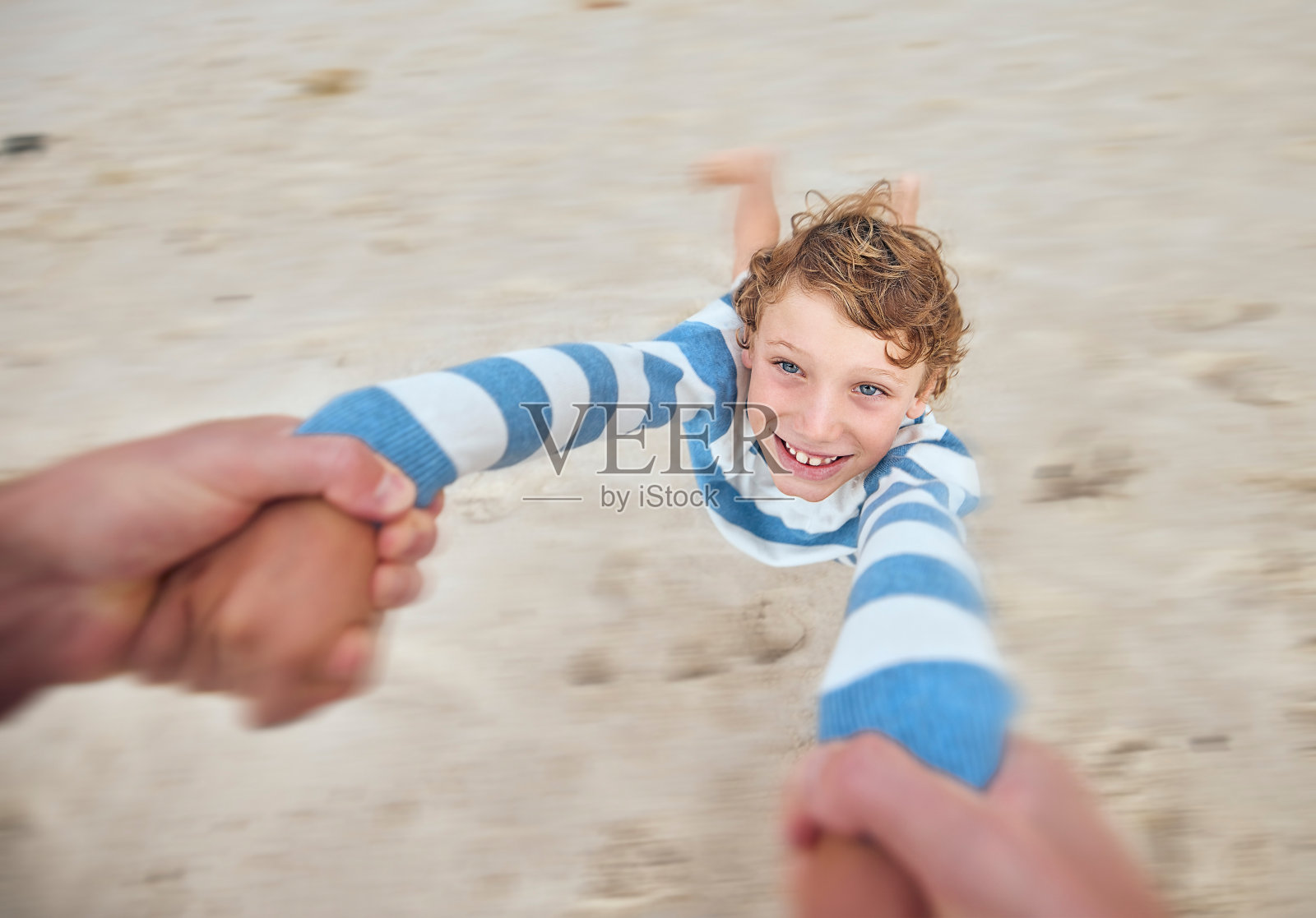 快乐的白人男孩摇摆和旋转的手臂在海滩岸边与他的父亲。可爱俏皮的孩子有乐趣的脸，而与家长在阳光明媚的暑假户外照片摄影图片