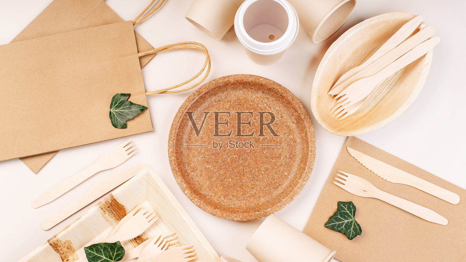 回收,环保的概念。一次性环保餐具，盘子，勺子，刀子，叉子放在一个明亮的背景上。用于食品递送的工艺纸袋。副本的空间。环保工艺纸餐具，杯子，快餐容器。照片摄影图片