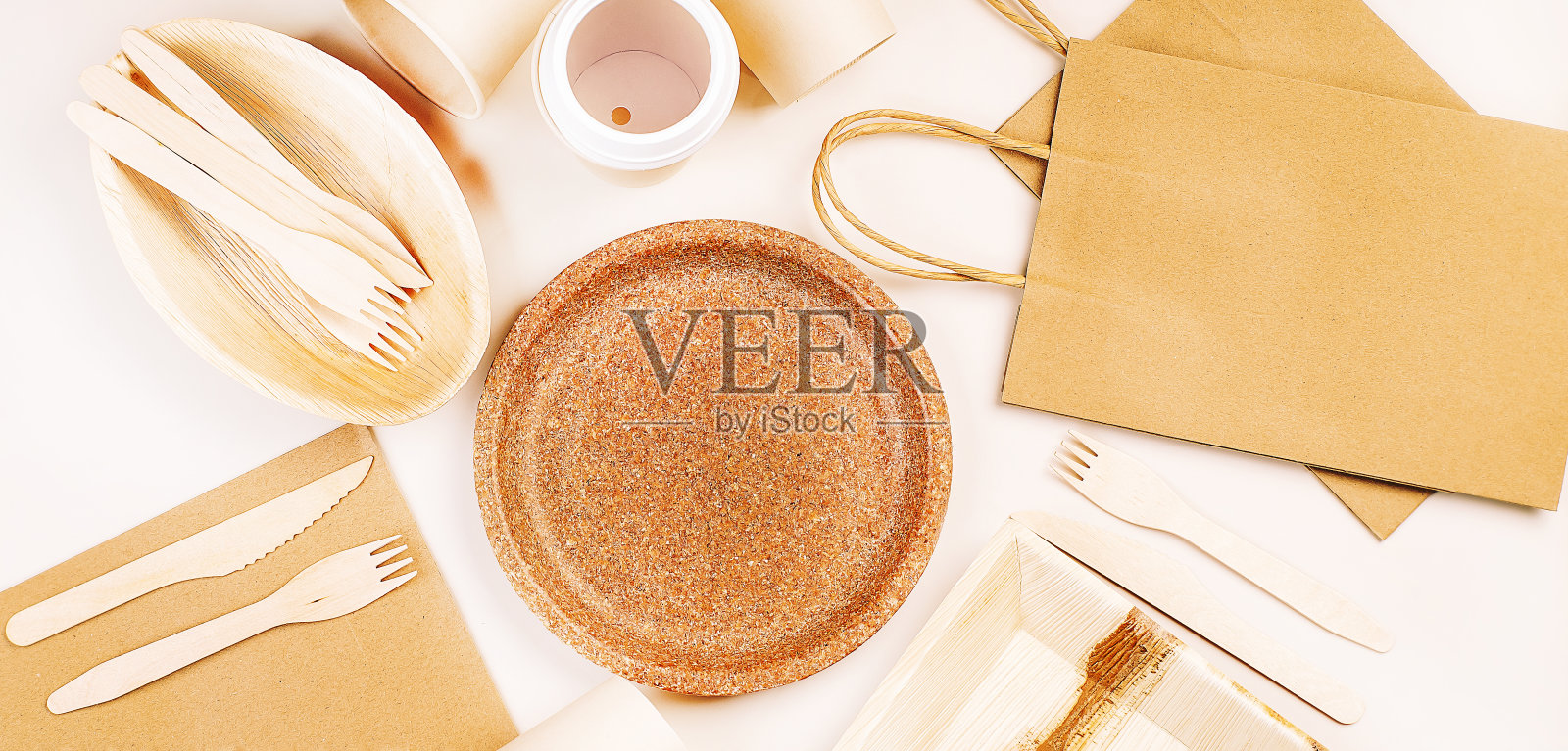环保工艺纸餐具，杯子，快餐容器。回收,环保的概念。一次性环保餐具，盘子，勺子，刀子，叉子放在一个明亮的背景上。用于食品递送的工艺纸袋。副本的空间。照片摄影图片