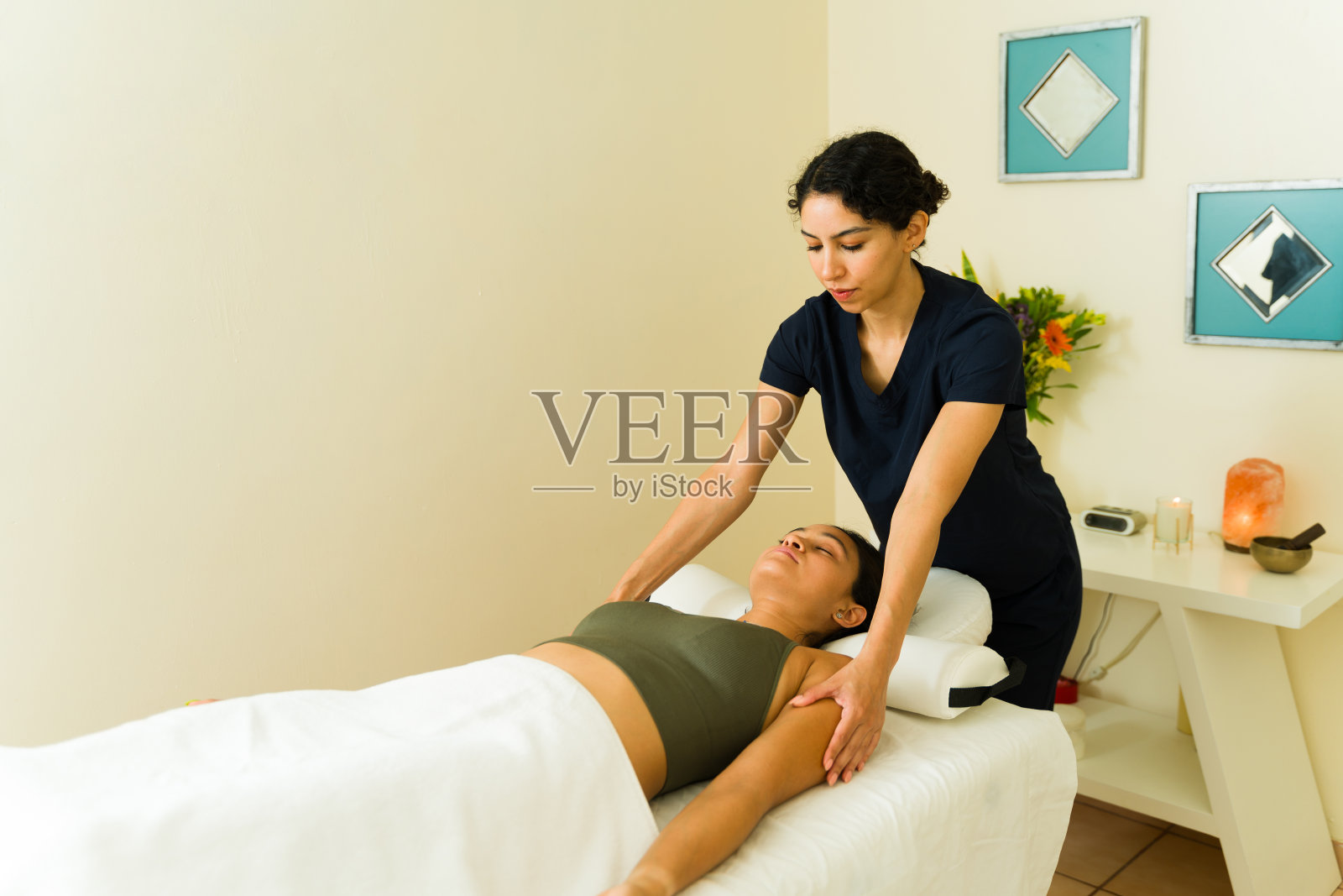 治疗师在水疗中心给一位放松的年轻女子按摩照片摄影图片