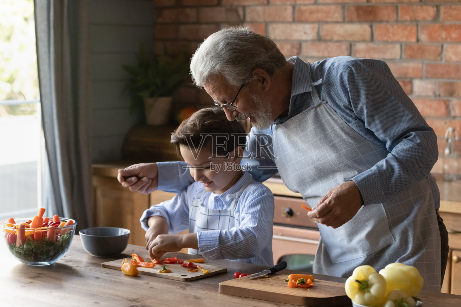 体贴成熟的爷爷教小孙子切菜照片摄影图片