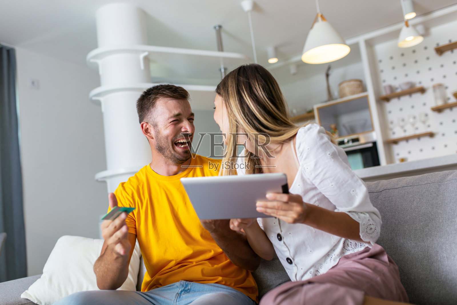 快乐的小情侣在家里用数字平板电脑和信用卡网购照片摄影图片