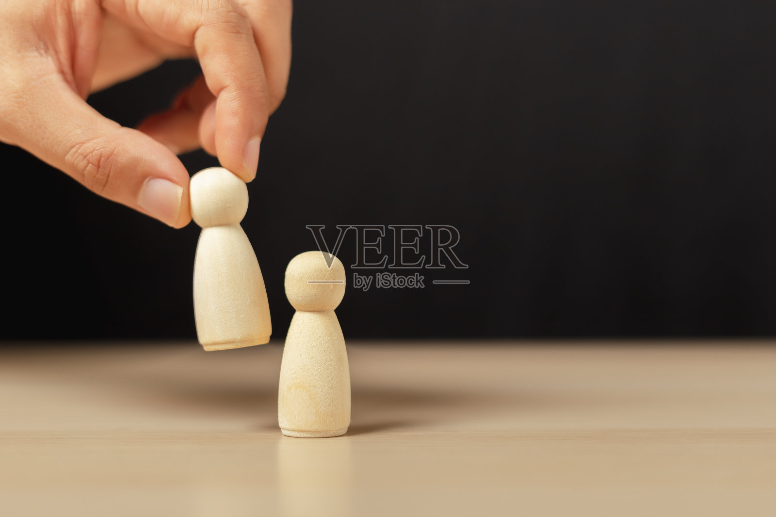 木头人被选为团队的领导者。人的双手是被挑选出来的木偶，用来设计任命领导人的策略。团队合作的领导理念。照片摄影图片