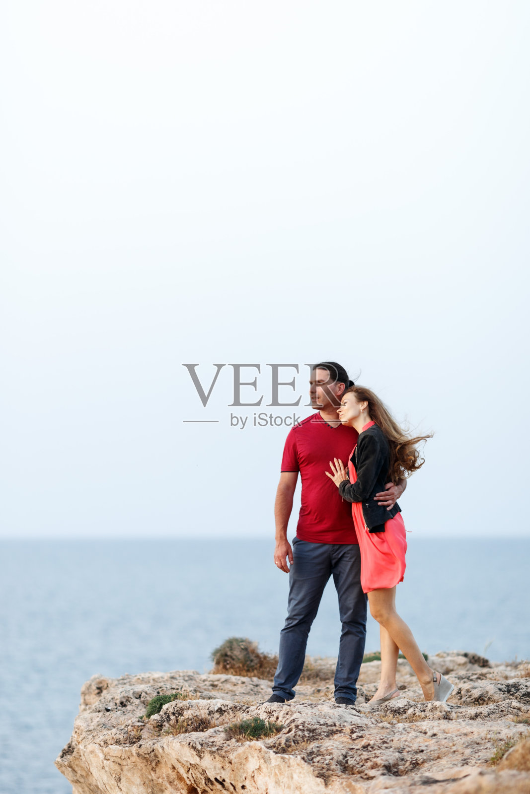 可爱的中年夫妇的肖像看着一边的copyspace和拥抱，而站在海边的岩石悬崖边照片摄影图片