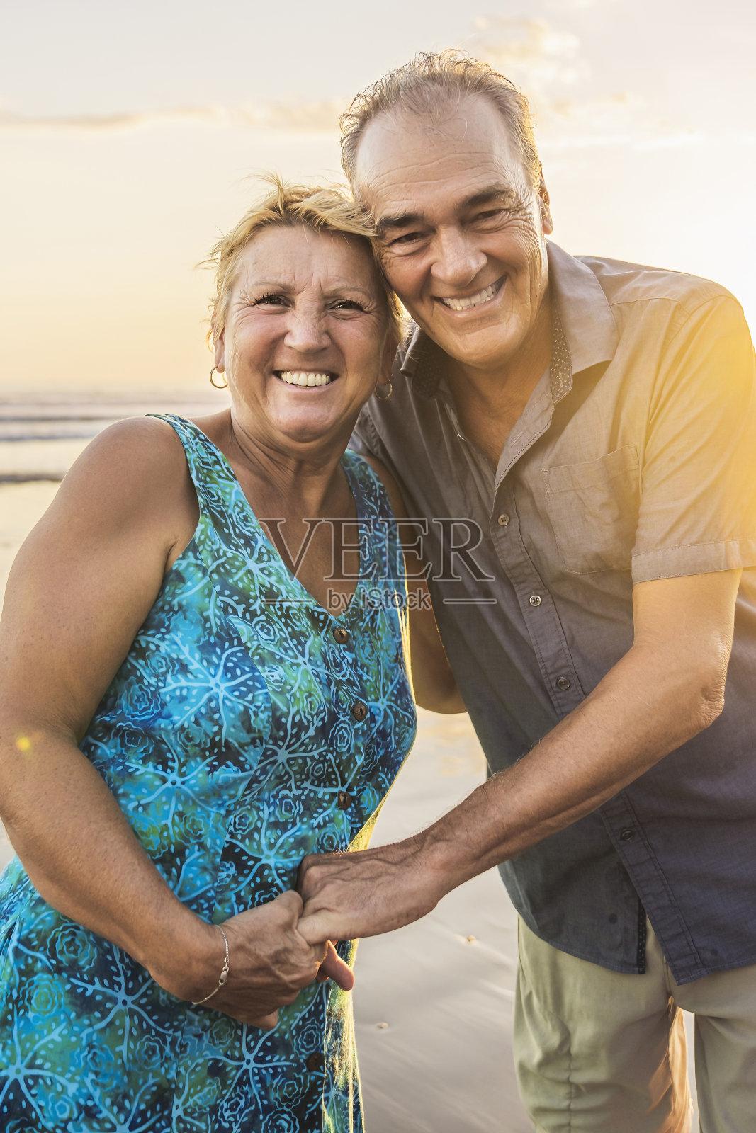 老夫妇在海滩上欣赏美丽的日落照片摄影图片