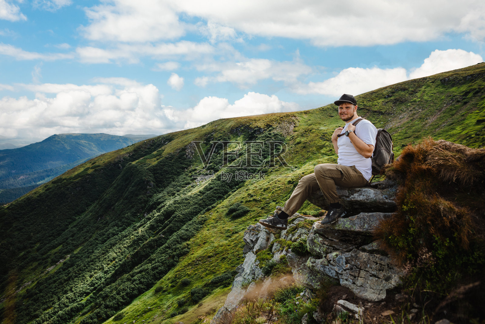 一个人坐在山顶的岩石上照片摄影图片