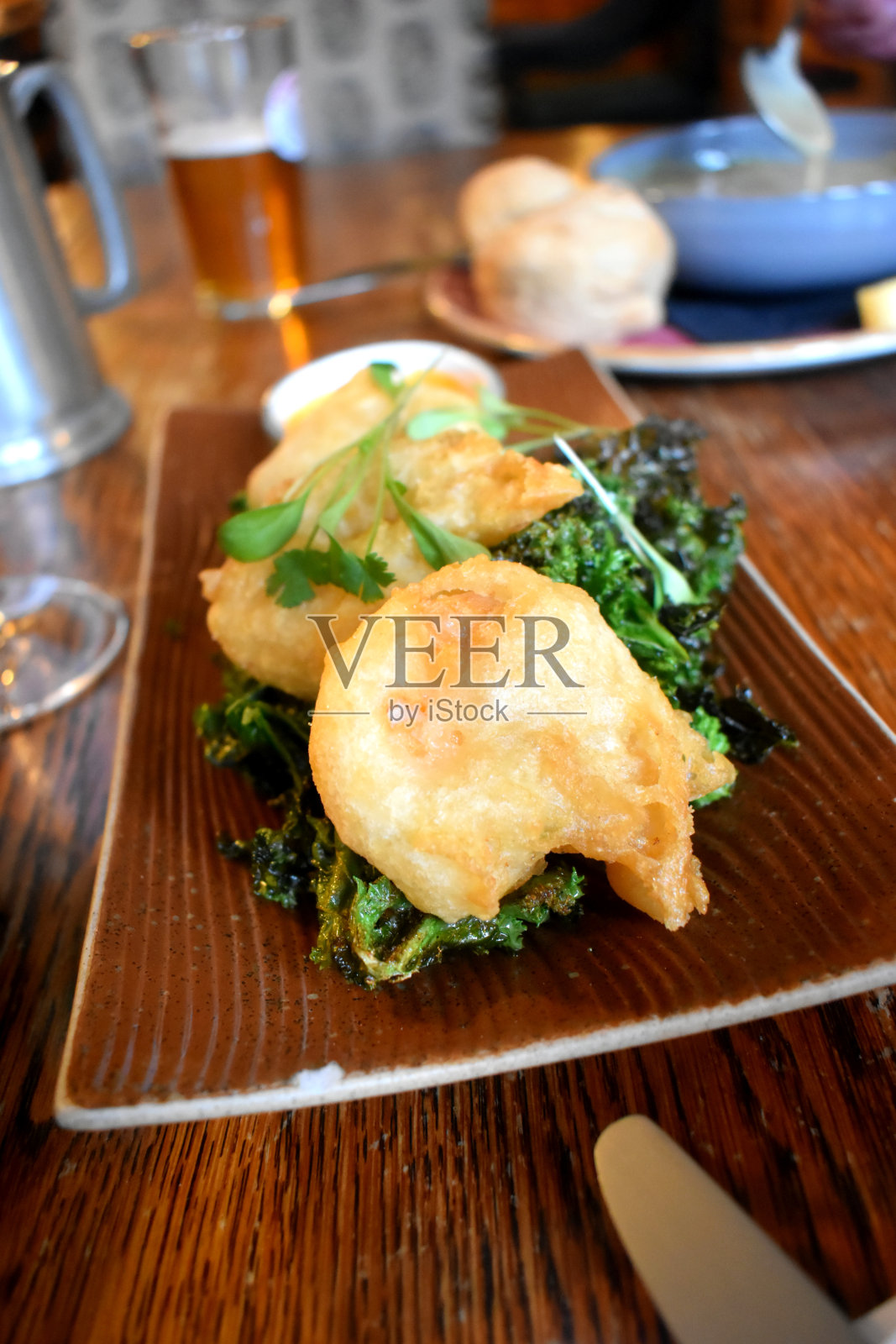 油炸天妇罗王对虾，烤绿海藻，棕色盘子，木桌。照片摄影图片