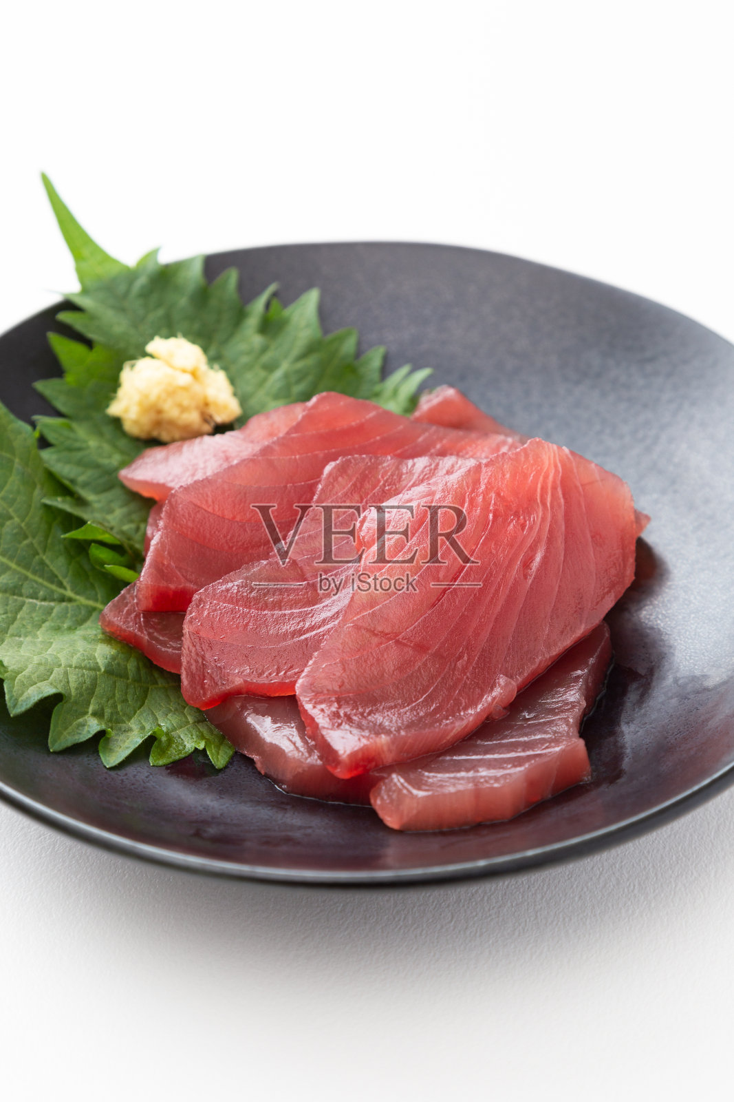 黑色盘子上的鲣鱼生鱼片。照片摄影图片