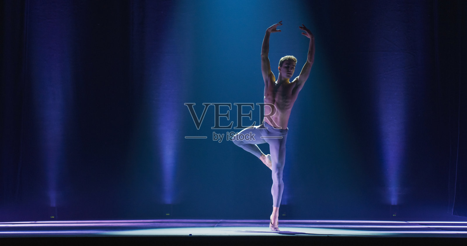 运动员在经典戏剧舞台上用戏剧性的灯光跳舞和排练脚尖旋转的广角电影镜头。优雅的古典芭蕾舞男舞者专业表演编舞照片摄影图片