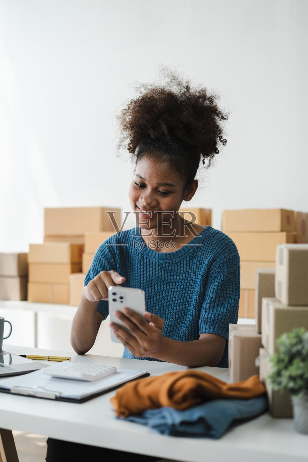 拿着智能手机的女人。在家工作的企业家。网上购物，电子商务，网上银行，消费，在家工作的概念。照片摄影图片