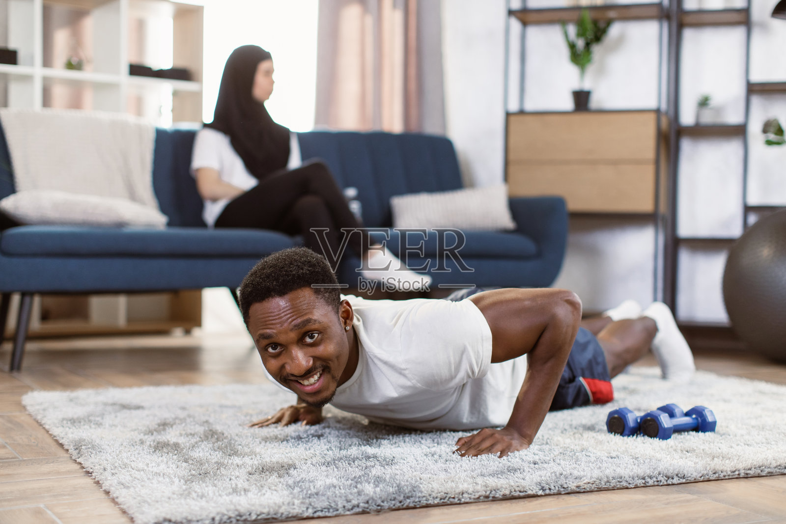 一个非洲人穿着运动服，笑容满面地挤在房间的地板上照片摄影图片