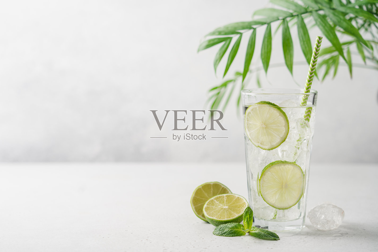 青柠莫吉托或柠檬水与冰在高杯与稻草在浅灰色的背景与复制空间。照片摄影图片
