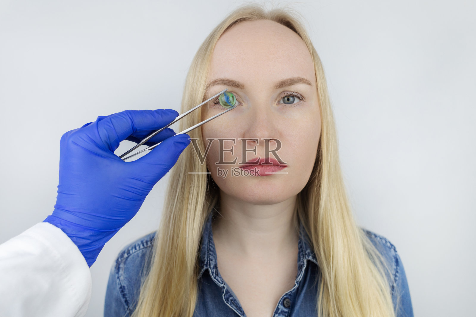 眼球晶体置换的概念性镜头。眼科手术。返回。去除白内障。眼球的外科干预。医生将植入物握在病人附近照片摄影图片