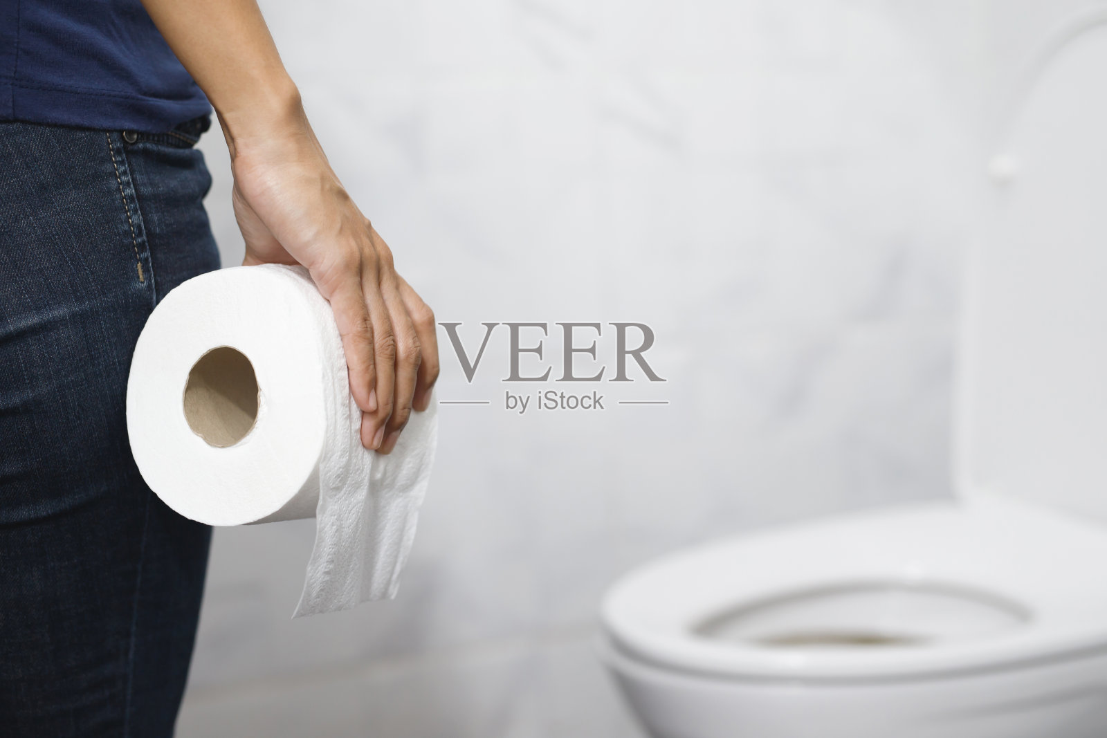 肖像中一名女子患有腹泻，他的胃很痛。疼痛和问题。手扶卫生纸卷在马桶前。浴室便秘。卫生、保健理念。照片摄影图片