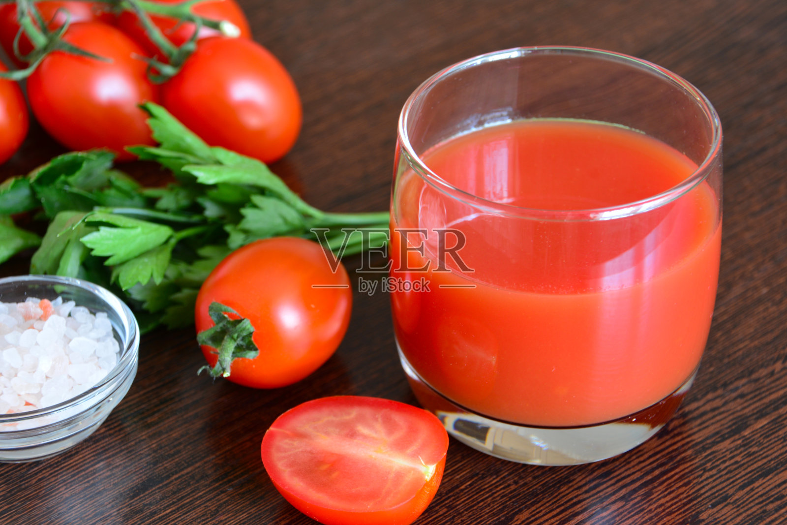 番茄汁、西红柿和一碗盐放在深色的木制背景上照片摄影图片
