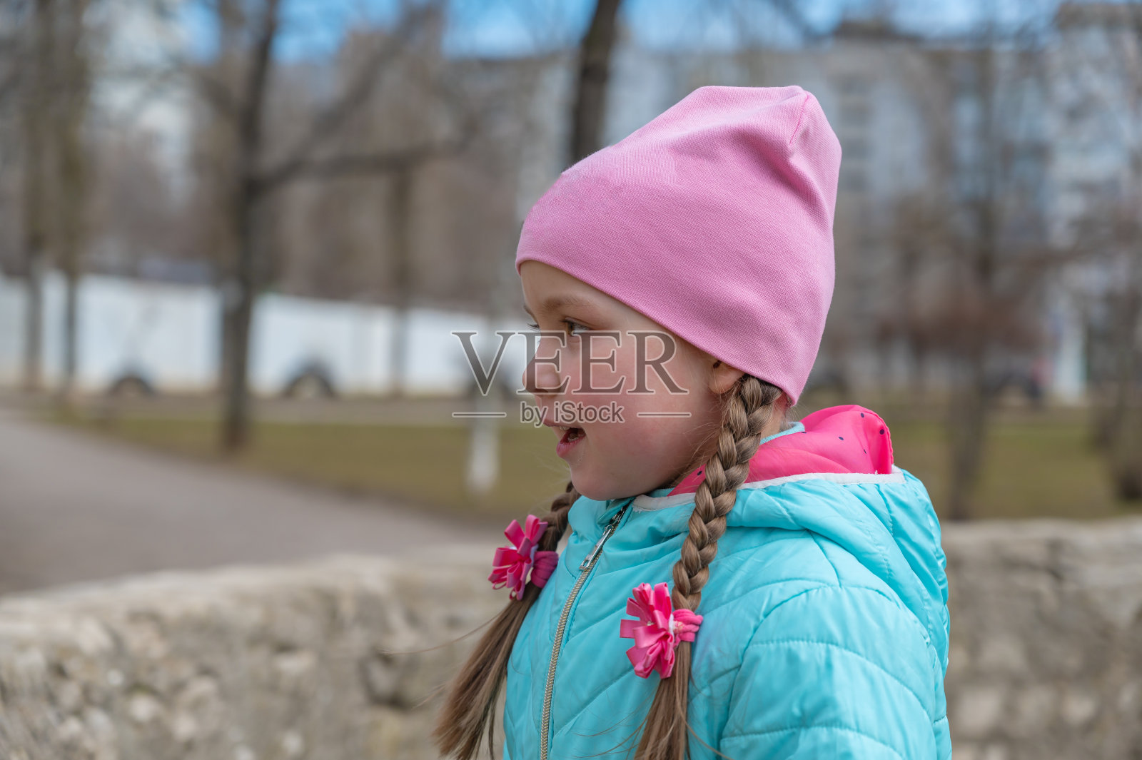 一个顽皮快乐的女孩的肖像。一个五岁的孩子把长发编成辫子。照片摄影图片