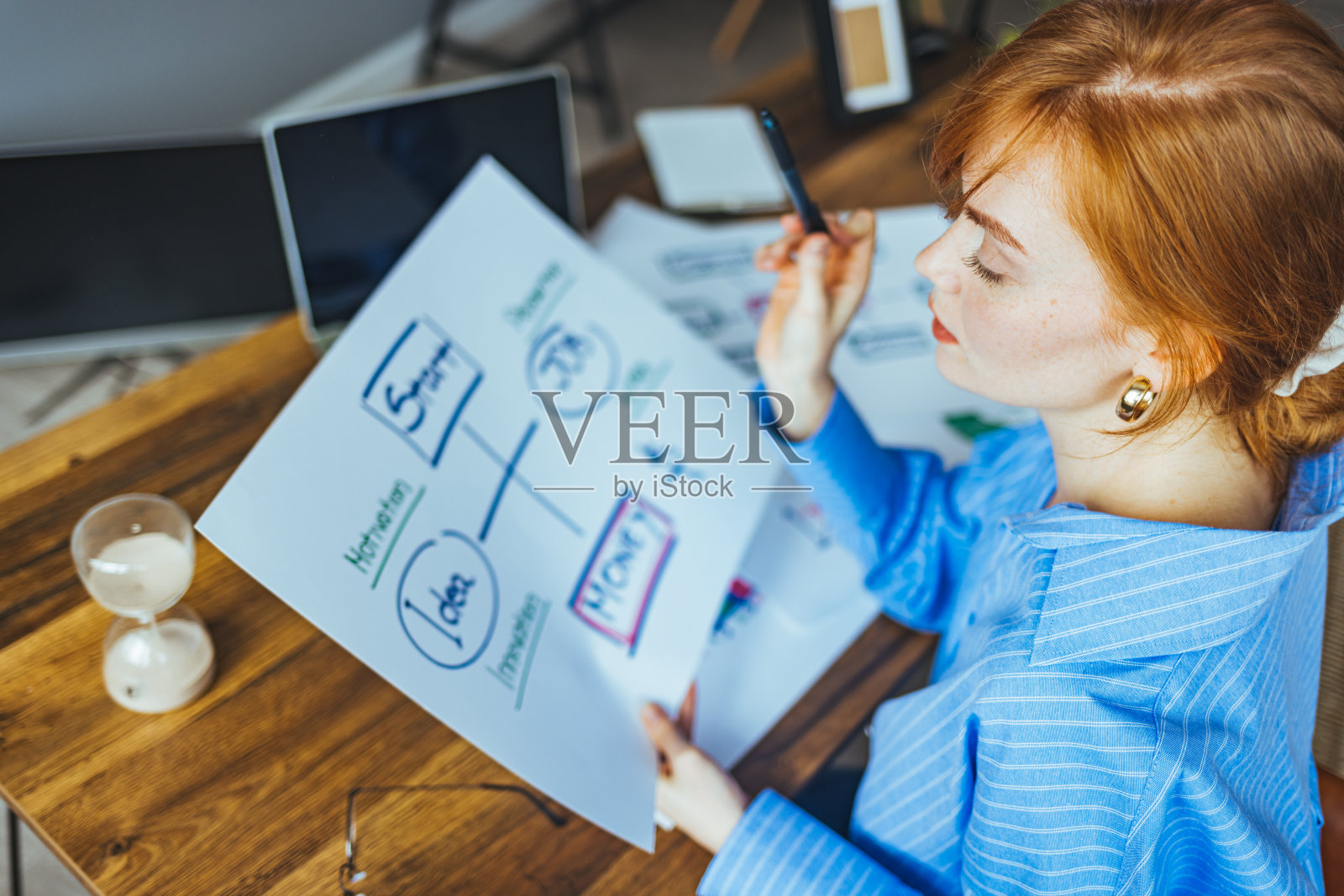 开朗的年轻女性用笔记本电脑和文件工作。照片摄影图片