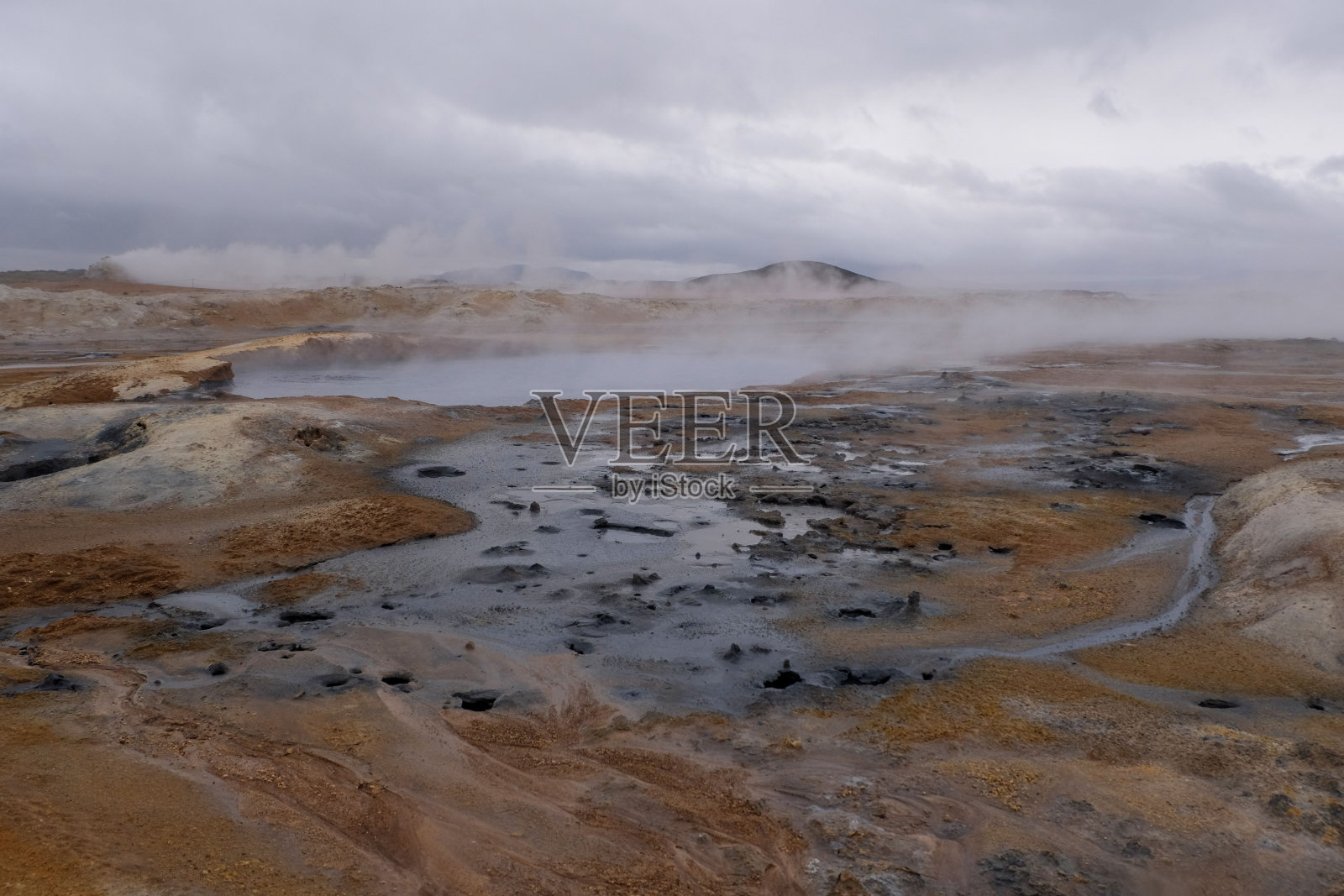 一幅风景画显示了一个温泉，背景是蒸汽上升照片摄影图片