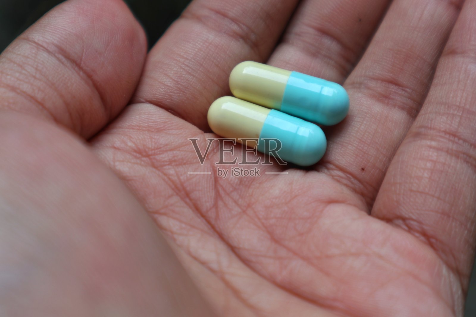 蓝色和白色的胶囊药丸在手照片摄影图片