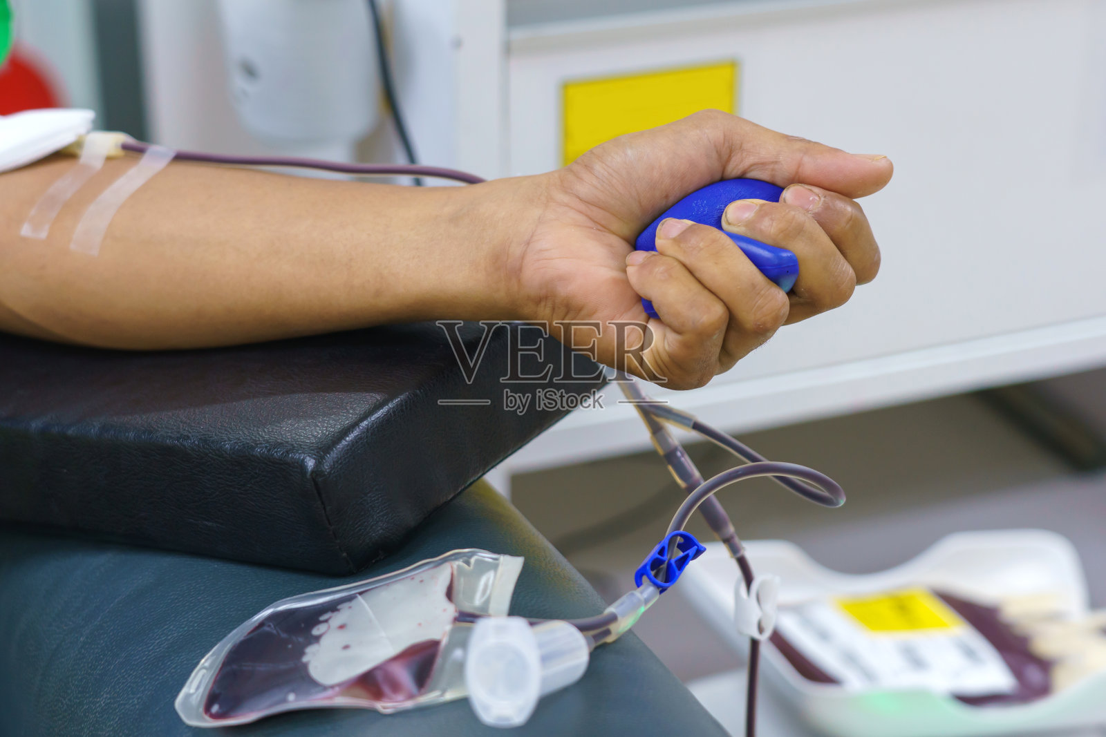 一名男子在献血时手里拿着一个弹跳球照片摄影图片