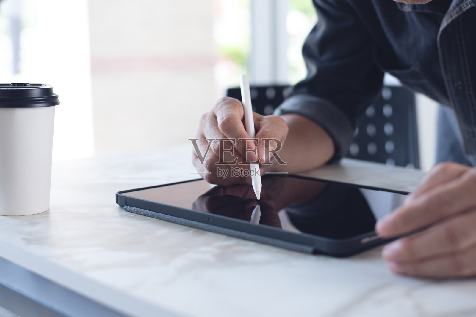 在家庭办公室的桌子上，用手写笔在数字平板电脑上签名的人手特写照片摄影图片