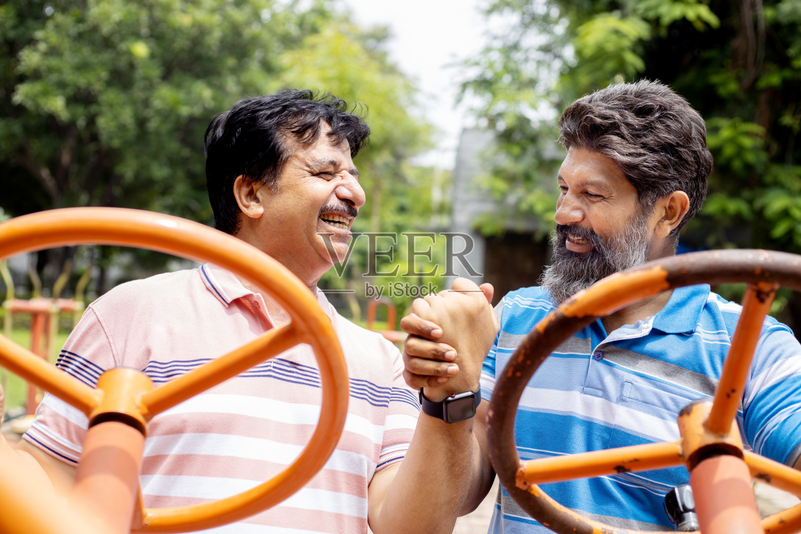 印度成熟的老年男子在公园户外健身器材上锻炼。照片摄影图片