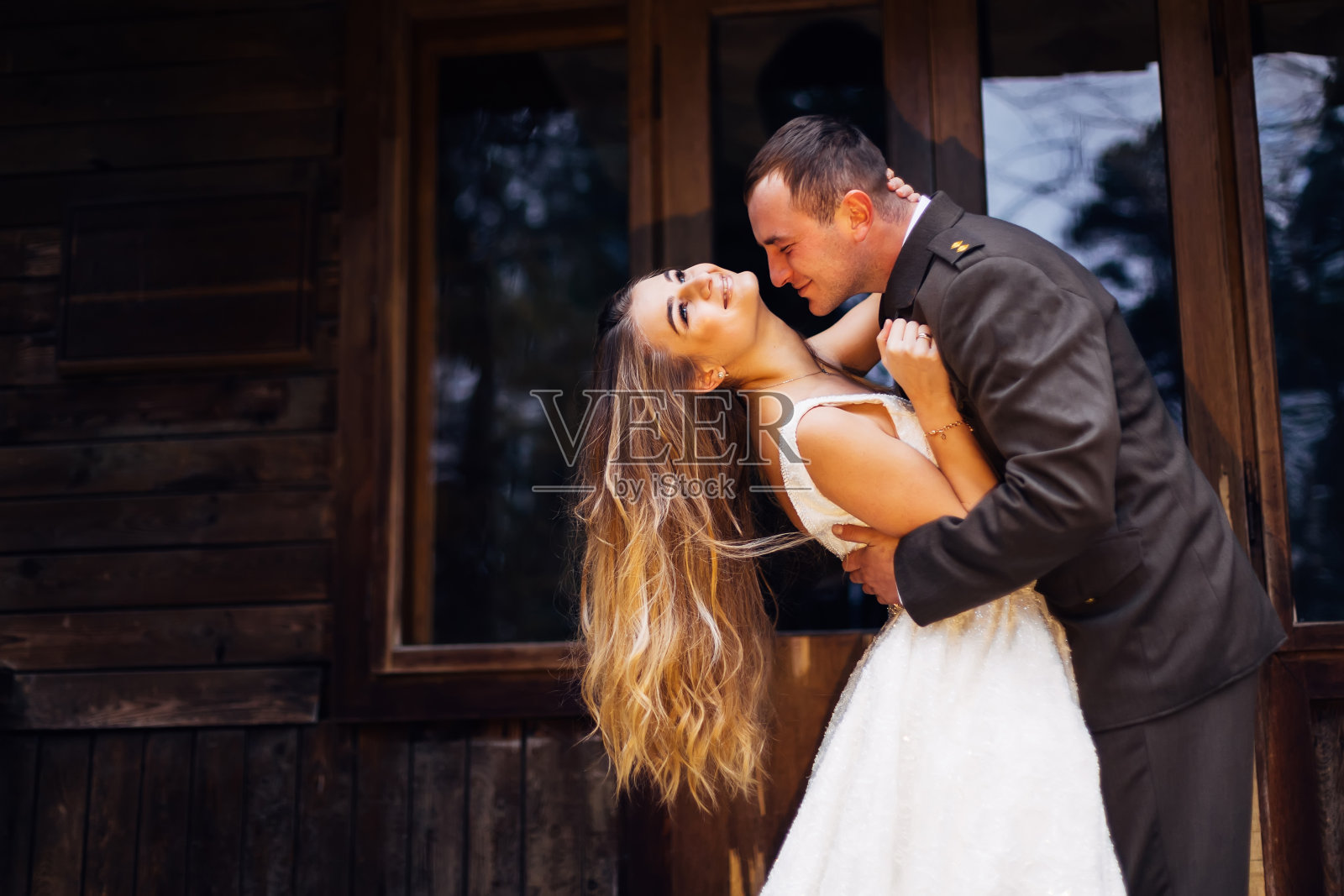 穿制服的新郎想要亲吻新娘，拥抱她的手照片摄影图片