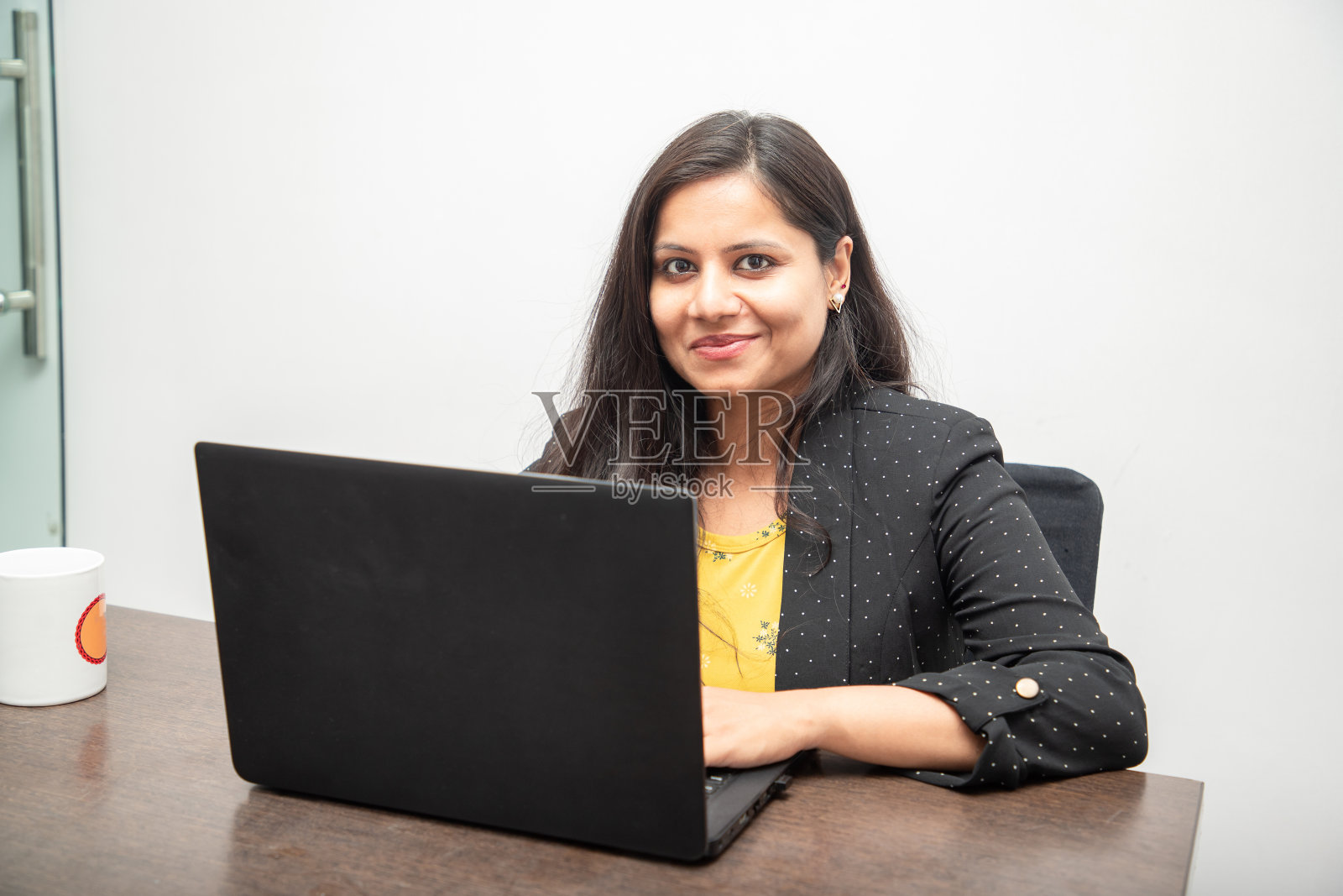 年轻的印度女商人在办公室用笔记本电脑工作的肖像。亚洲企业女性使用电脑看着相机照片摄影图片
