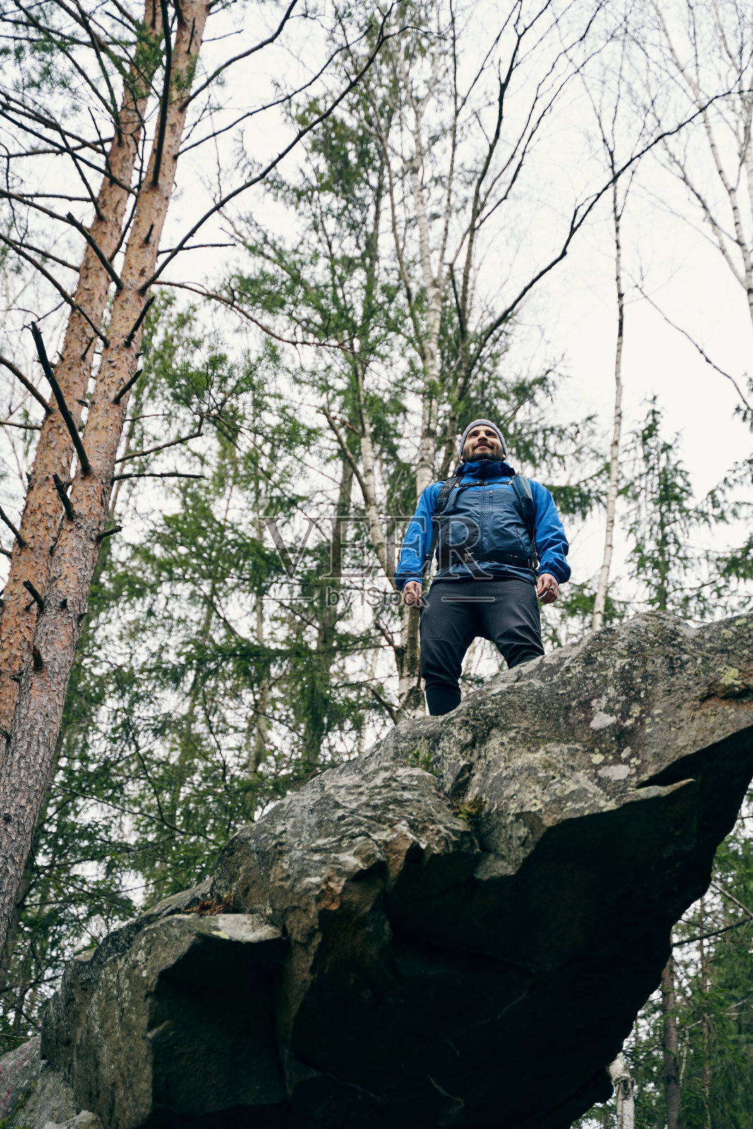 满意的男性徒步旅行者在岩石山顶检查森林照片摄影图片