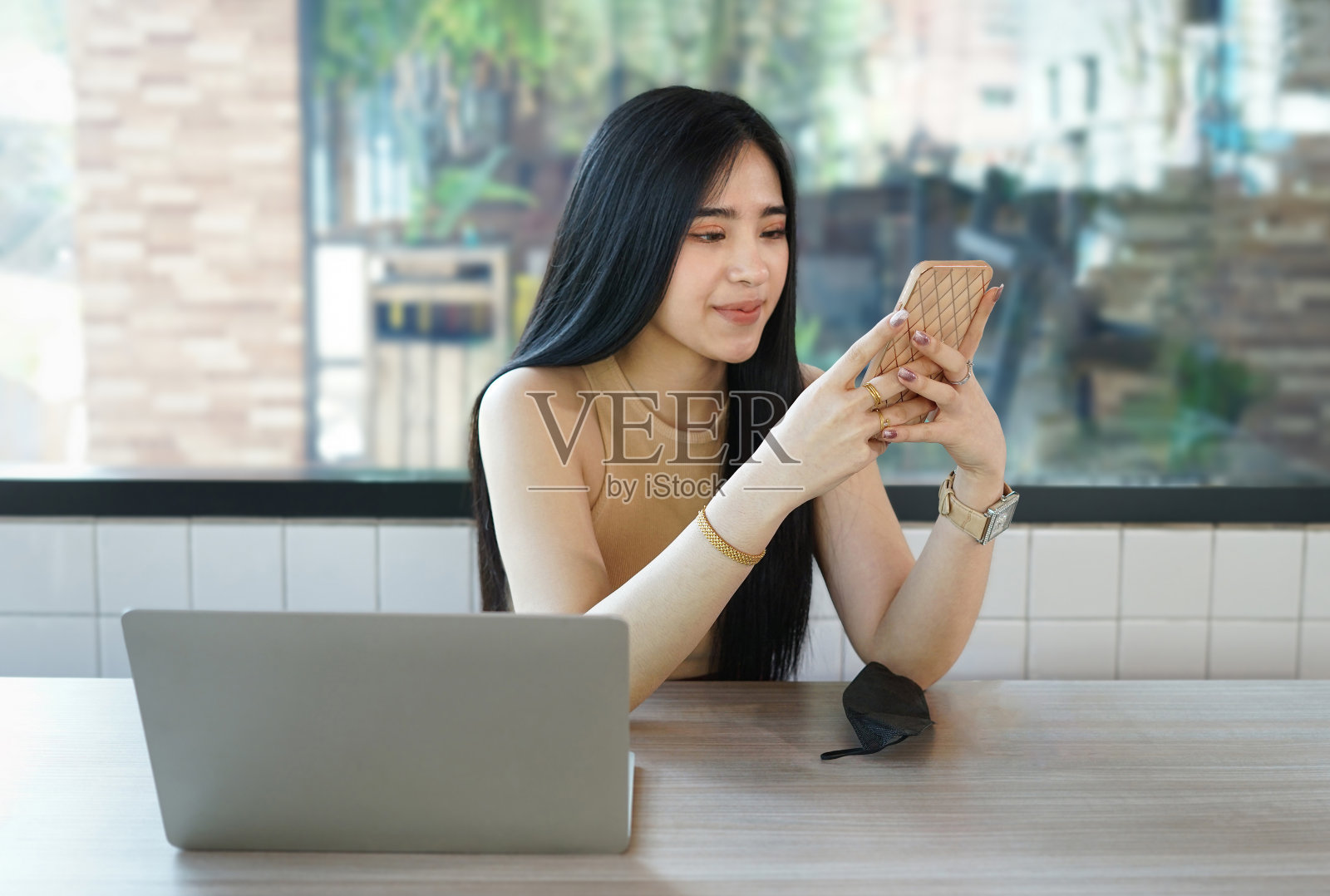 年轻的亚洲女性在室内咖啡馆用笔记本电脑和智能手机工作，概念数字游牧民，在办公室外工作照片摄影图片