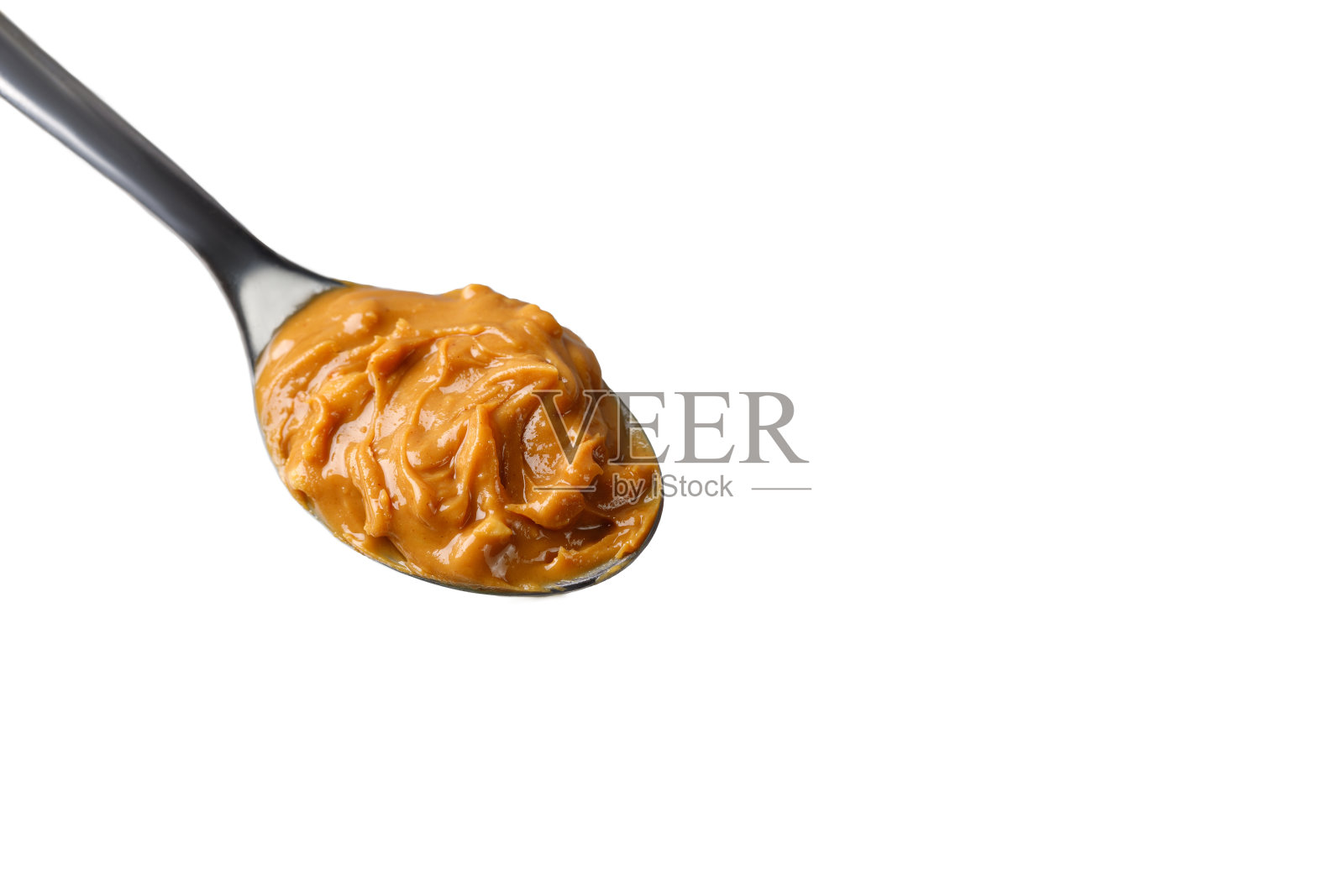 花生酱放在勺子上。甜花生酱酱。质地,关闭。照片摄影图片