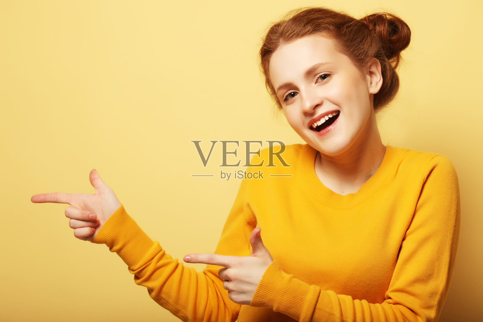 一个漂亮女孩的肖像指着黄色的后背照片摄影图片