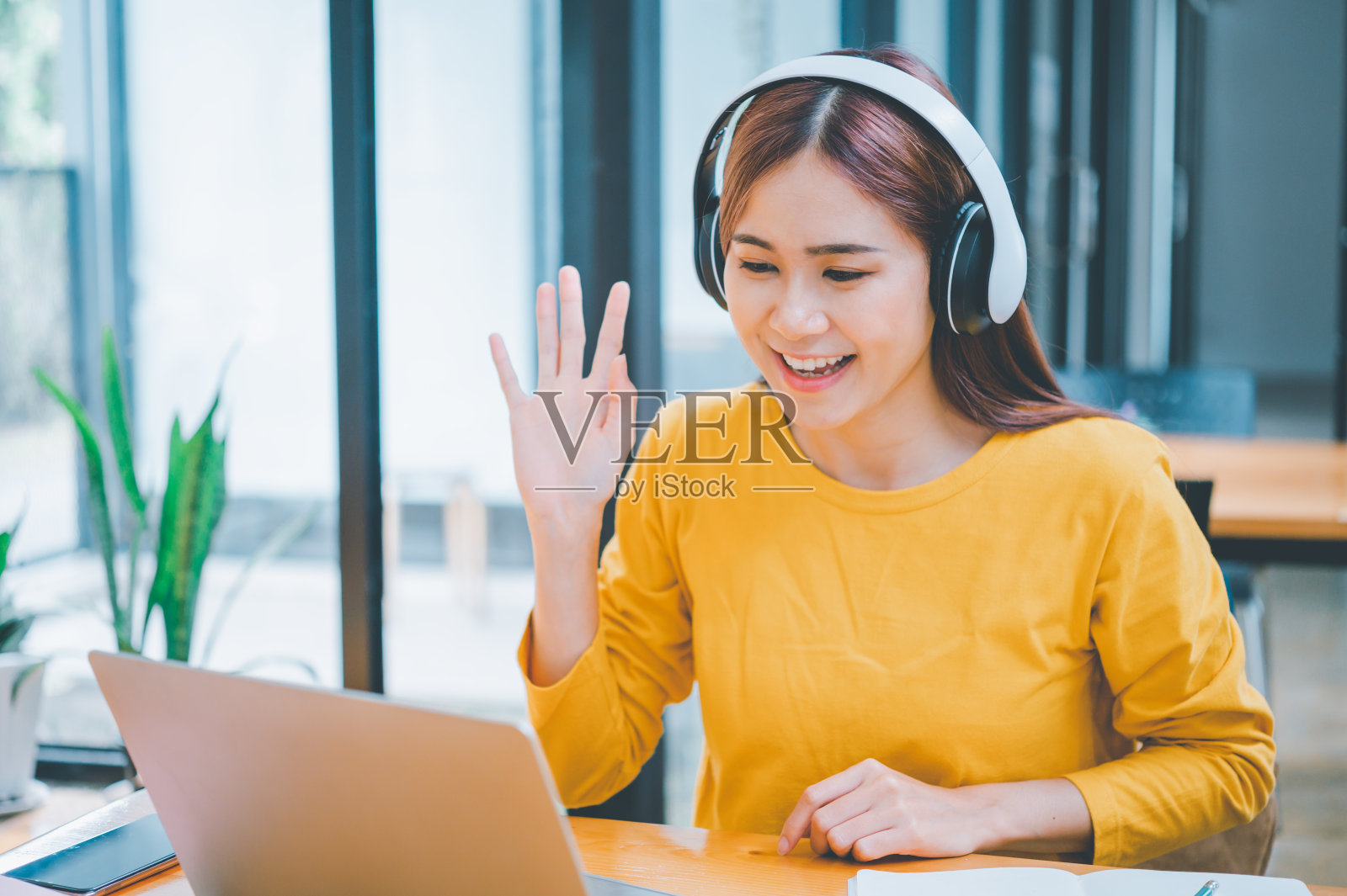 戴着耳机的年轻学生在线学习，远程学习，并了解全球冠状病毒大流行的最新情况。照片摄影图片