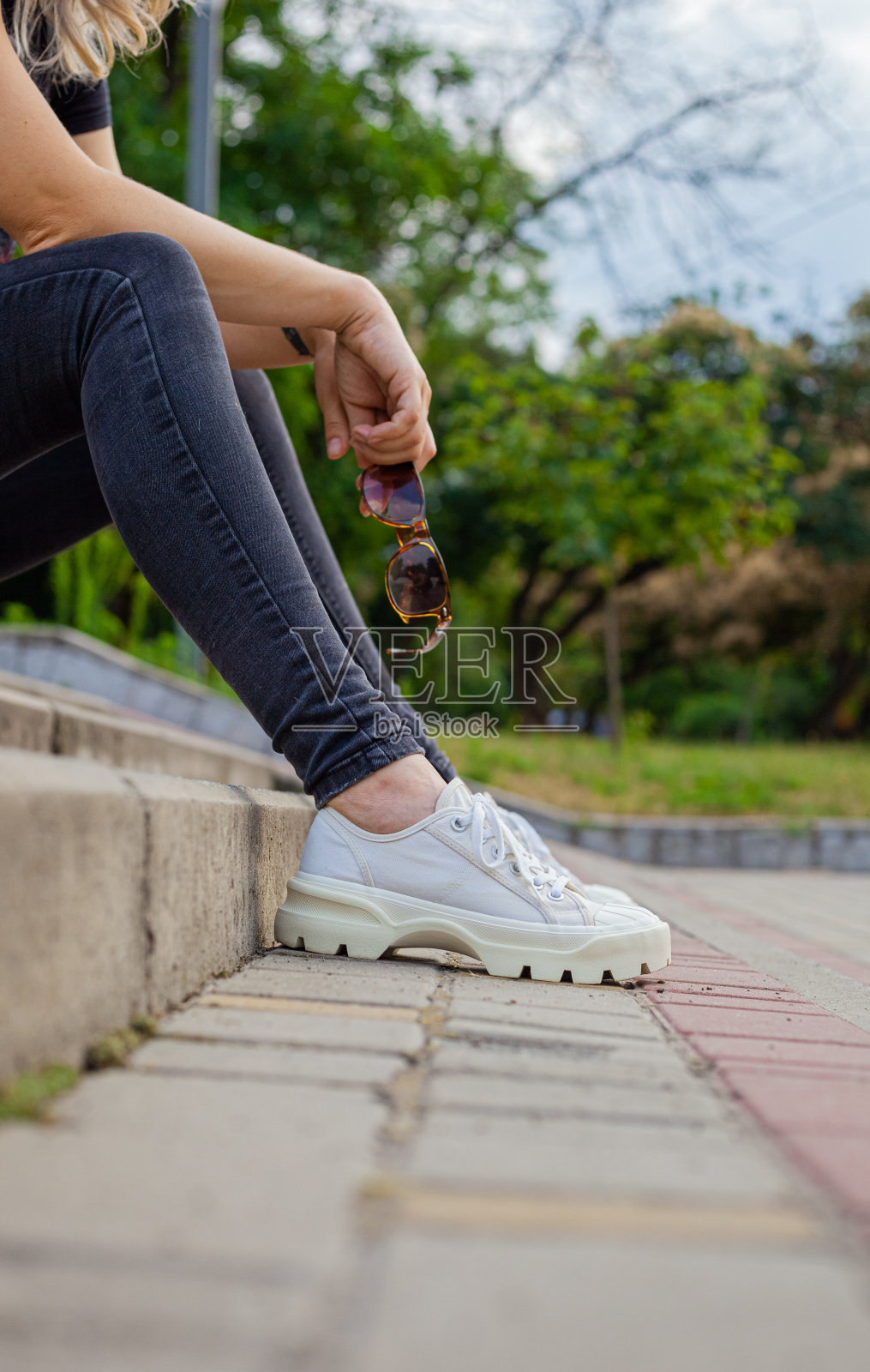 女孩坐在台阶上，手里拿着墨镜照片摄影图片