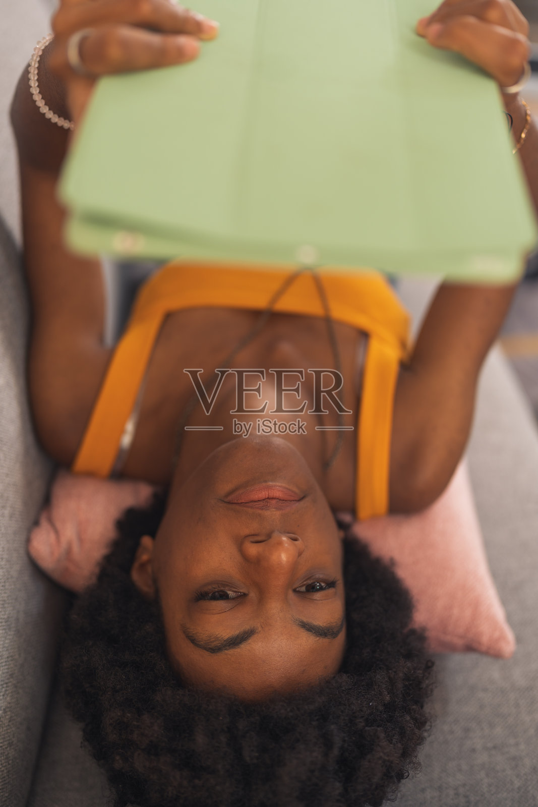 年轻的黑人女性躺在床上玩她的电子平板电脑照片摄影图片