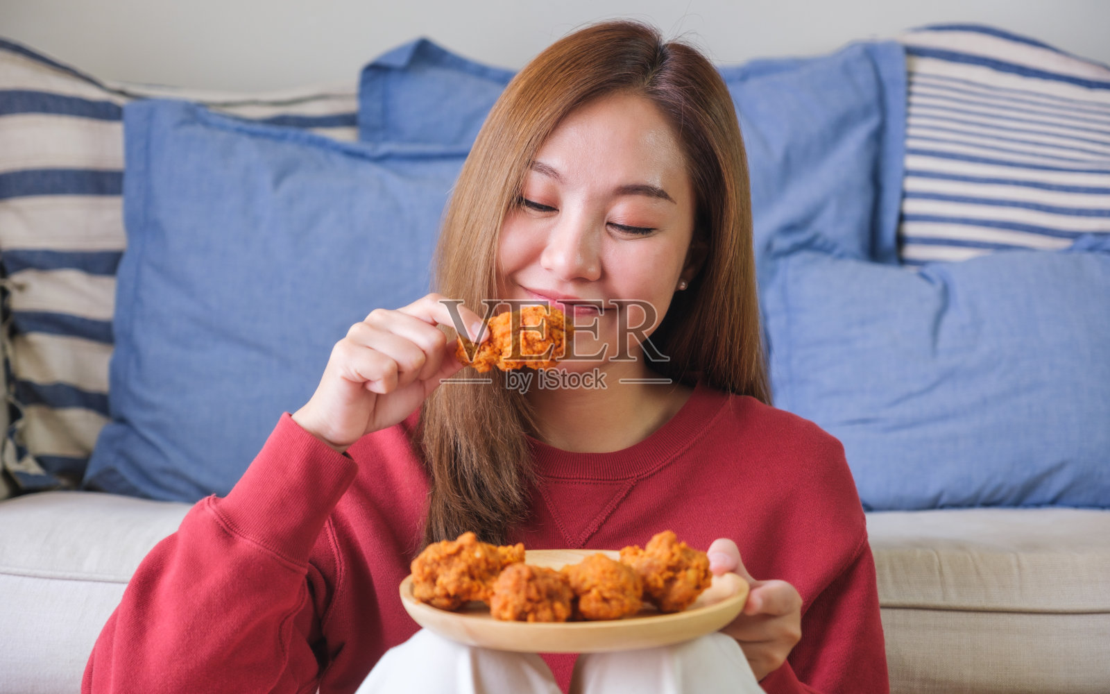 一个年轻女子在家里拿着炸鸡吃的画像照片摄影图片