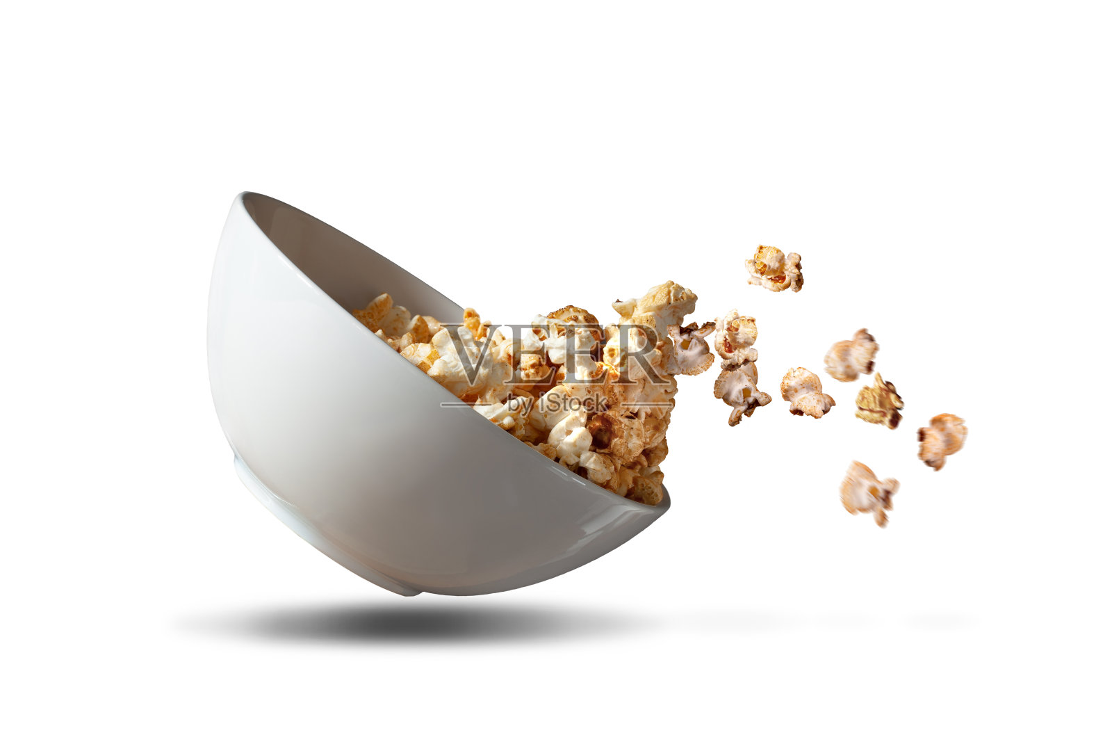 爆米花从一个白色的碗里掉出来照片摄影图片