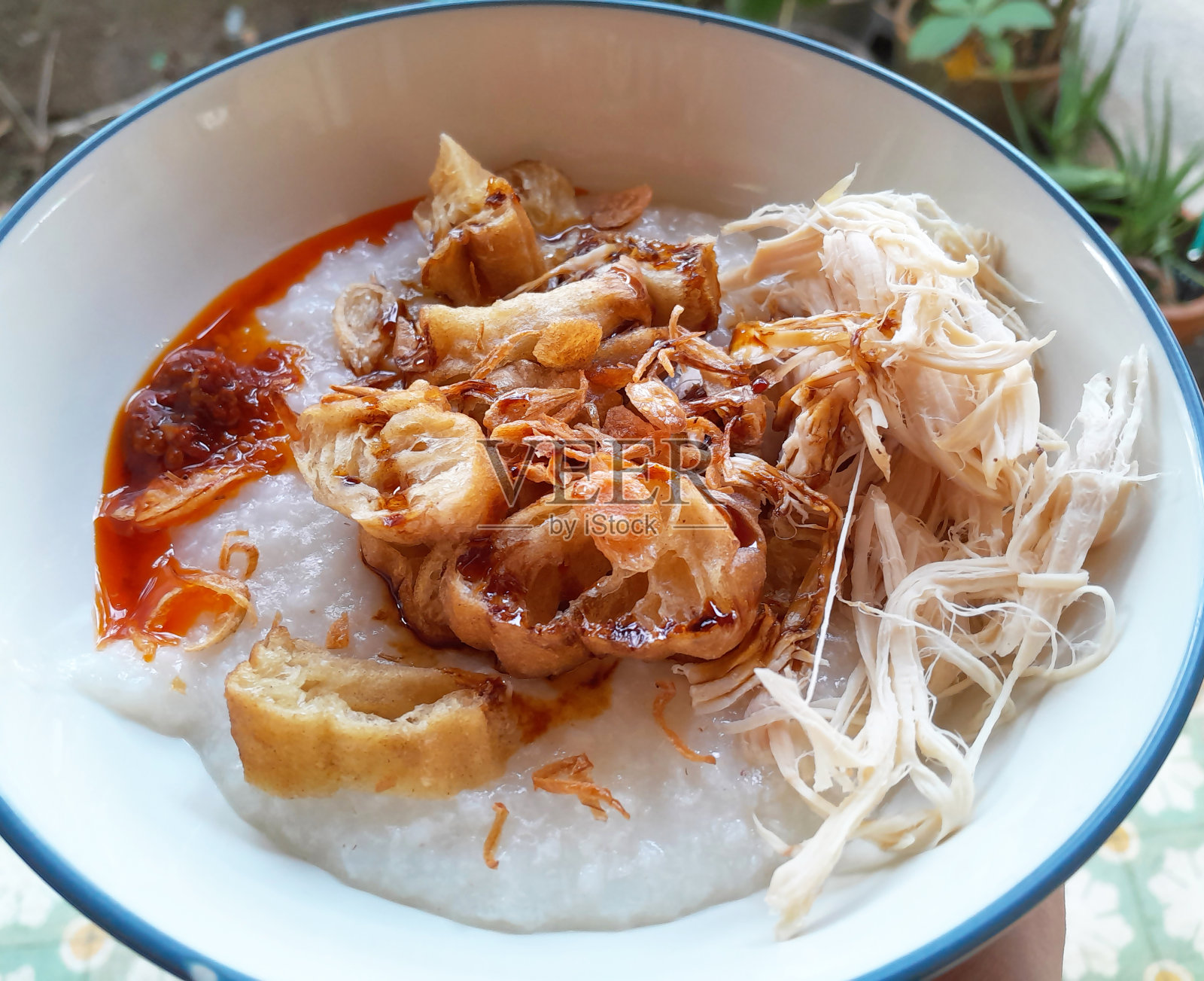 鸡肉粥或bubur ayam是一种鸡肉米粥，通常作为早餐食用。它通常包含鸡肉、切片饼或油条面包、甜酱油或酱汁、空饼干和红辣椒辣酱，上面撒上霸王goreng。照片摄影图片